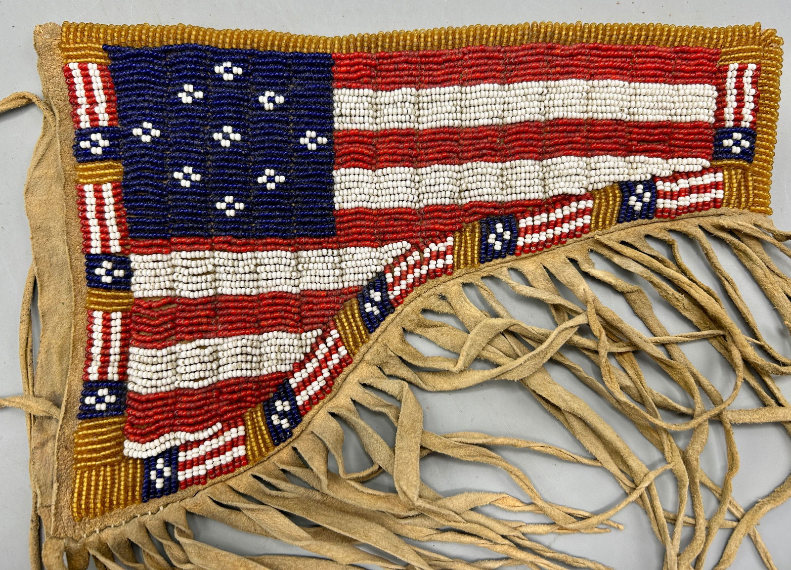 A Native American Beaded Pistol Holster: A 9 inch Native American bead decorated buckskin pistol holster with an American flag motif. In good condition for its age.