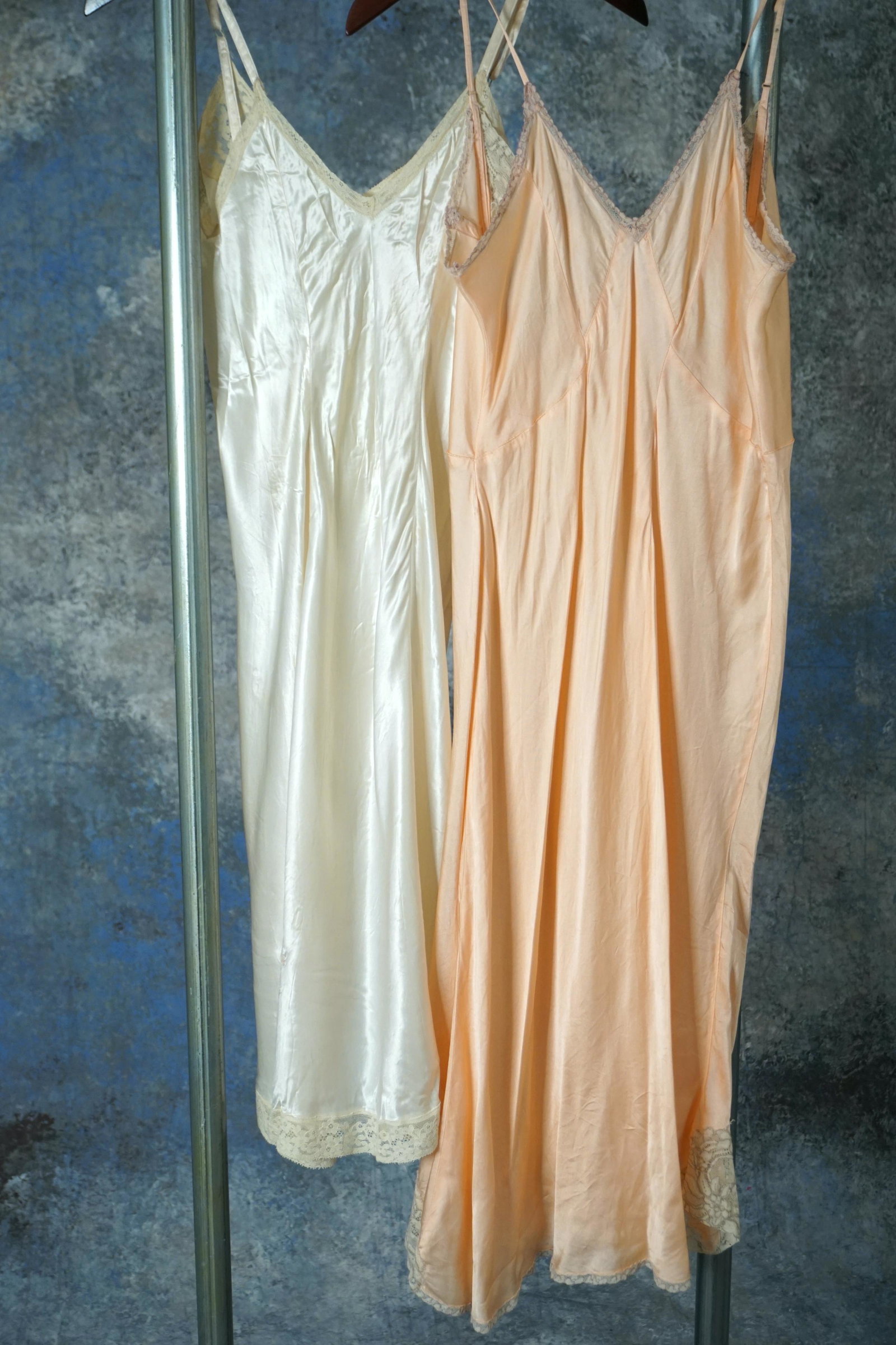 Vintage 1920s lingerie dresses lot of two: Vintage 1920s silk satin and rayon satin negligee dress lot of two pieces. White dress is decorated with lace trim and floral bow motif. Measures 32” bust, 24-25” waist, 38” length. 