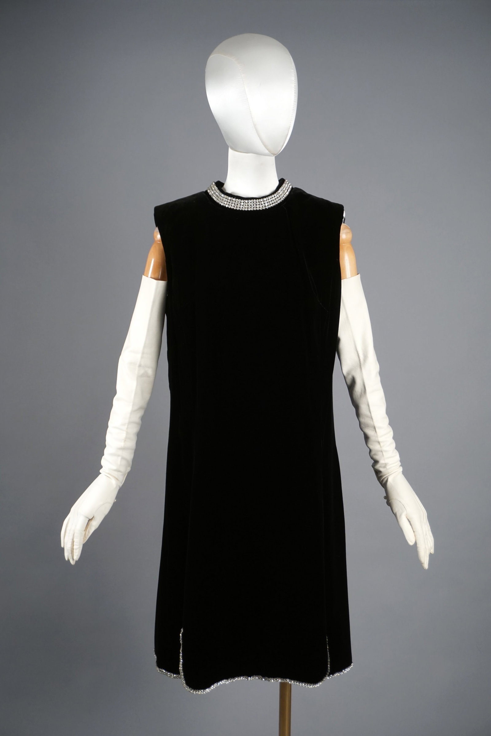 Vintage Black Velvet Dress with Rhinestone Embellishments: Circa 1960s black velvet and rayon shift dress featuring a sleeveless design and a clean, minimalist silhouette. The neckline is adorned with an elegant row of rhinestones, creating a statement collar