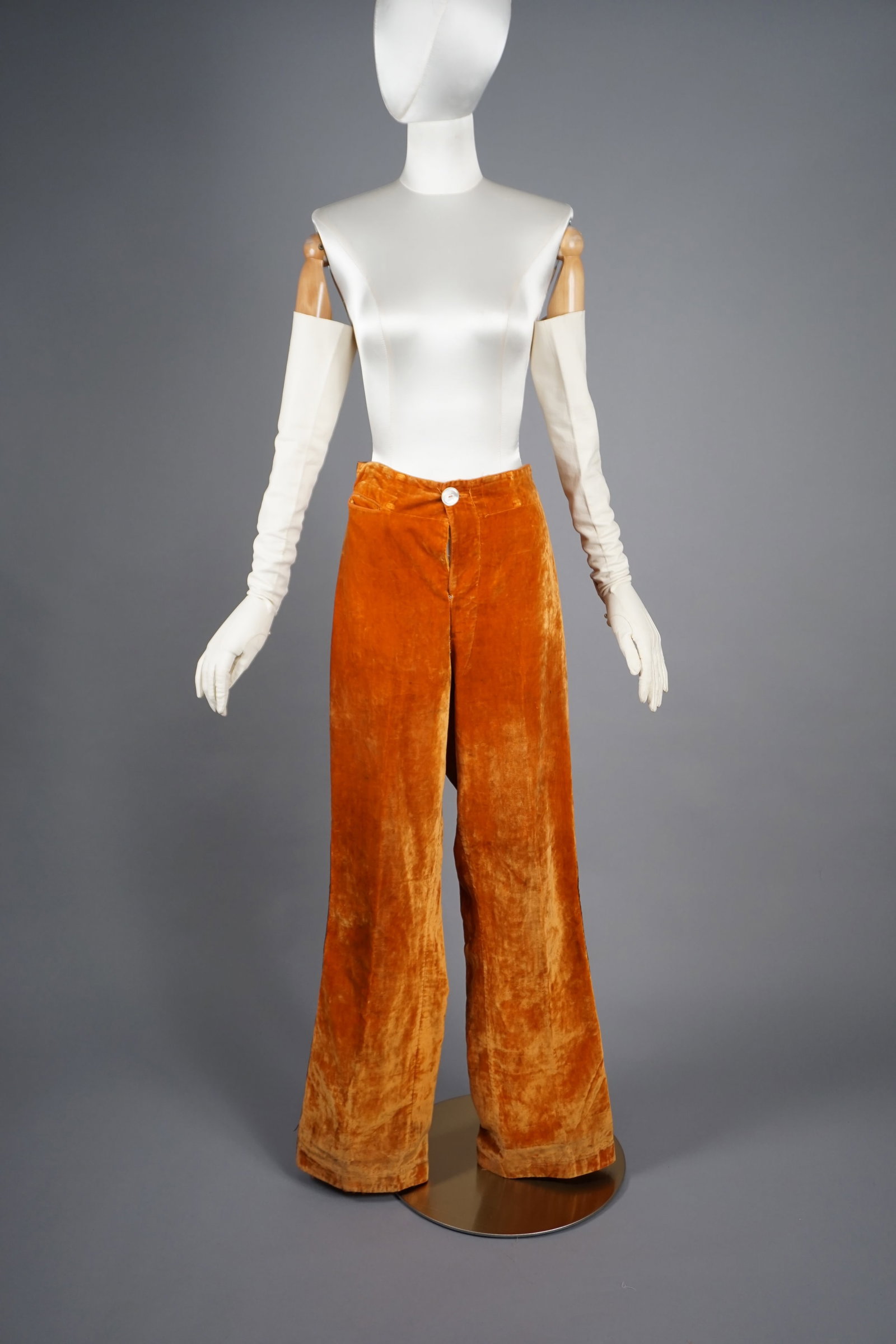 Antique 1900s Orange Velvet Pants with Metal Embroidery: Antique 1900- 1920 pants crafted from rich, burnt-orange velvet, showcasing a luxurious texture and deep patina developed over time. The trousers feature a single-button front closure with a prominent