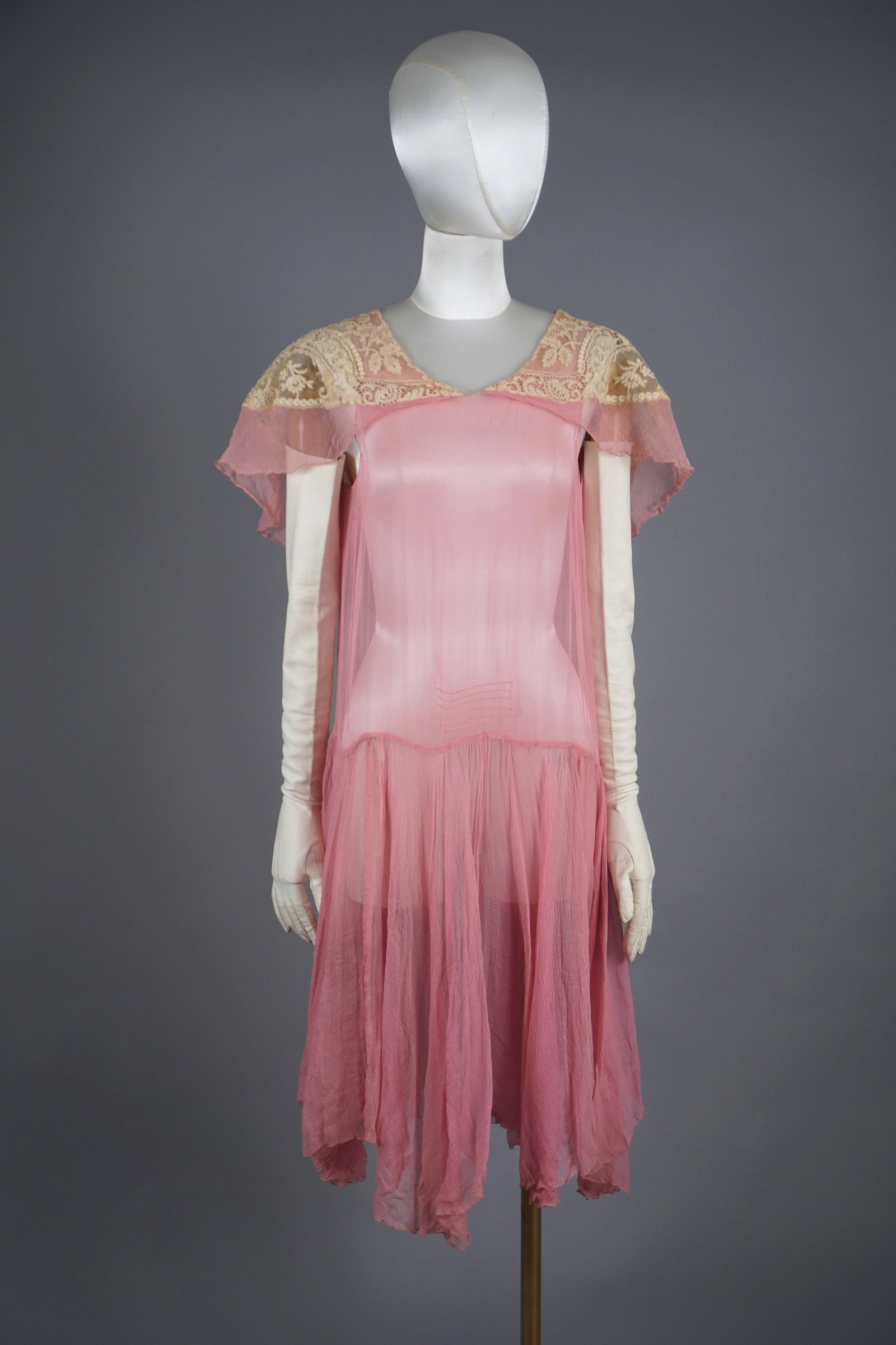 Vintage 1920s Pink Silk Chiffon Dress with Ecru Lace Capelet: A delicate 1920s silk chiffon dress in soft pastel pink. The bodice is adorned with an intricate ecru lace capelet, extending over the shoulders and upper back, showcasing ornate floral and medallion 