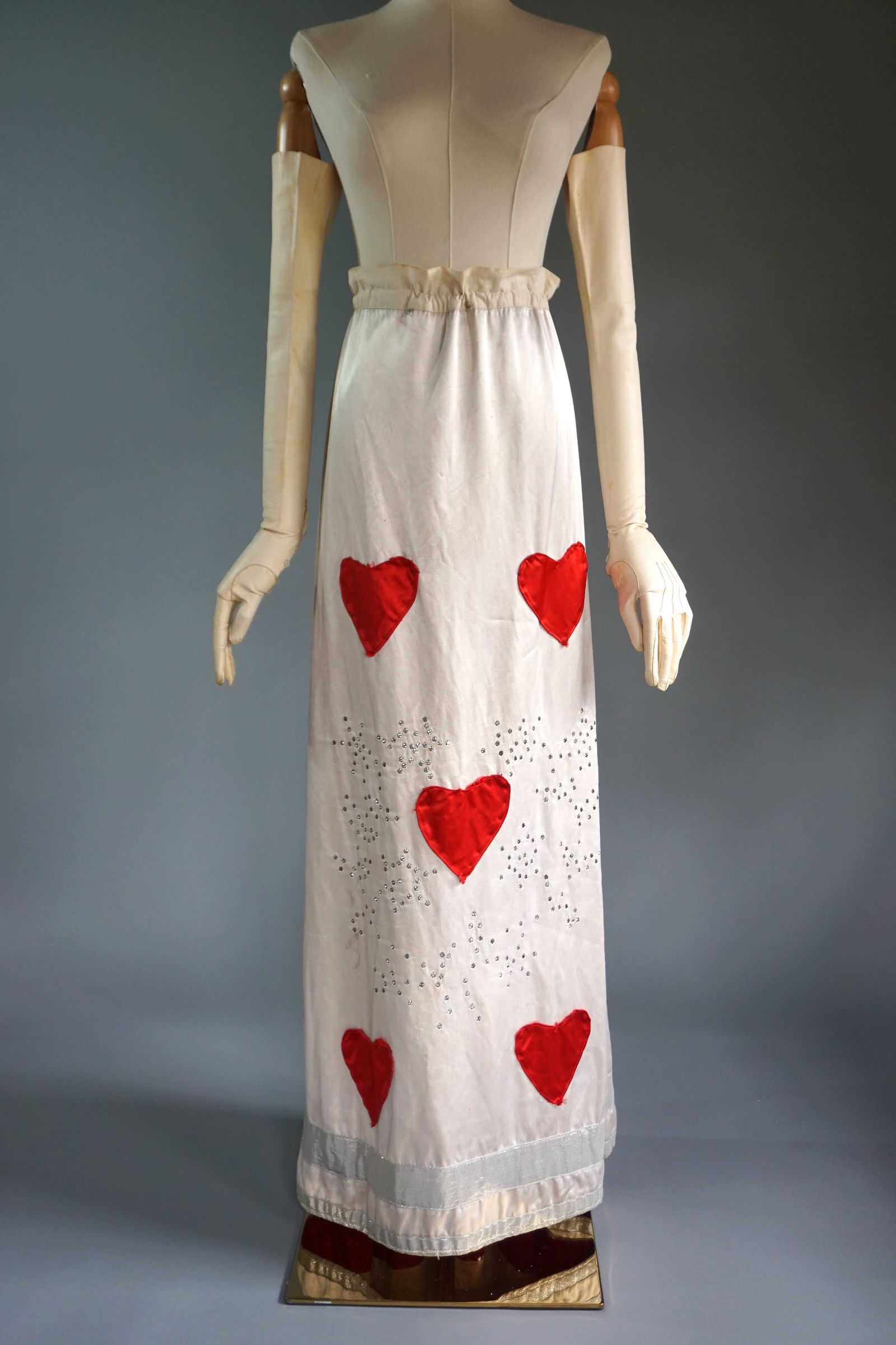 Vintage White Satin Costume Skirt with Red Heart Appliqués, Rhinestone Embellishments, 20th c.: Early- mid 20th-century costume skirt made of luxurious white satin with a Victorian era linen backing. The design features striking red satin heart appliqués symmetrically placed on the front, creat