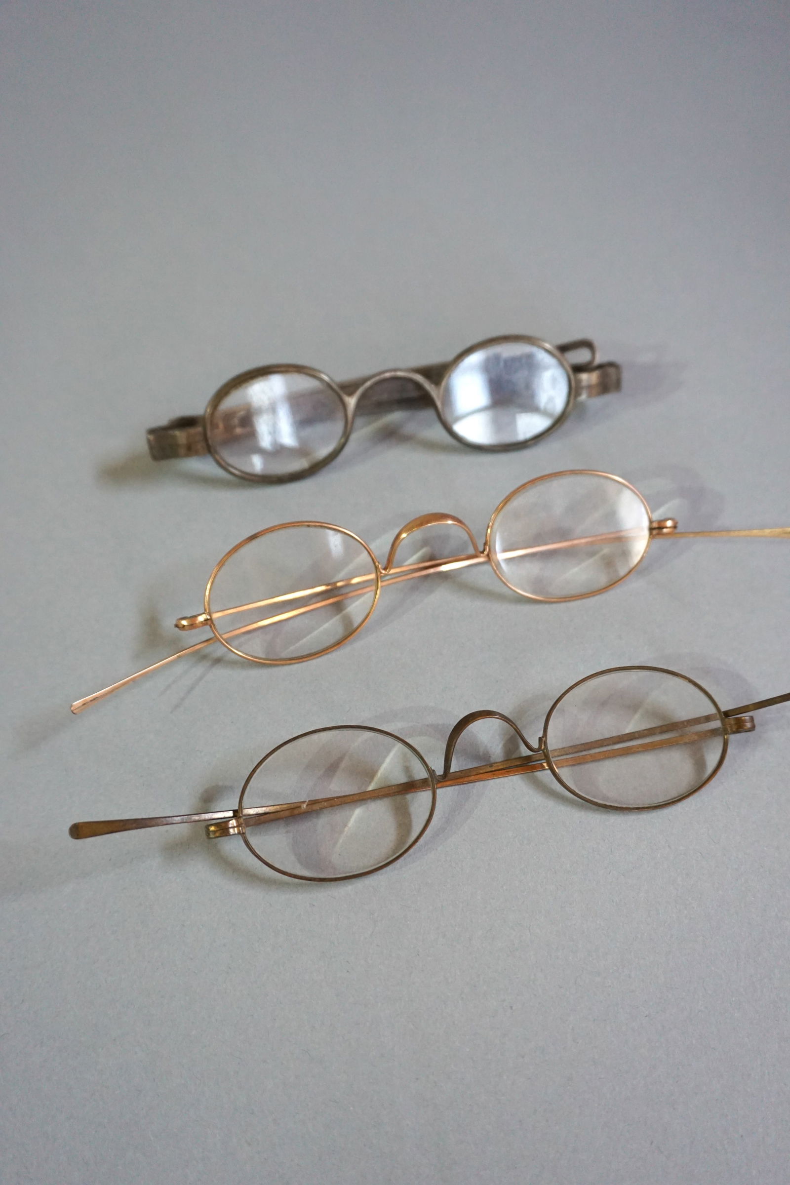 Lot of Three Antique Eyeglasses, Early 19th- 20th Century: Lot of three antique eyeglasses, dating from the mid-19th century to the early 20th century, each showcasing distinct historical craftsmanship and materials. Mid-19th Century Sliding Temple Eyeglasses