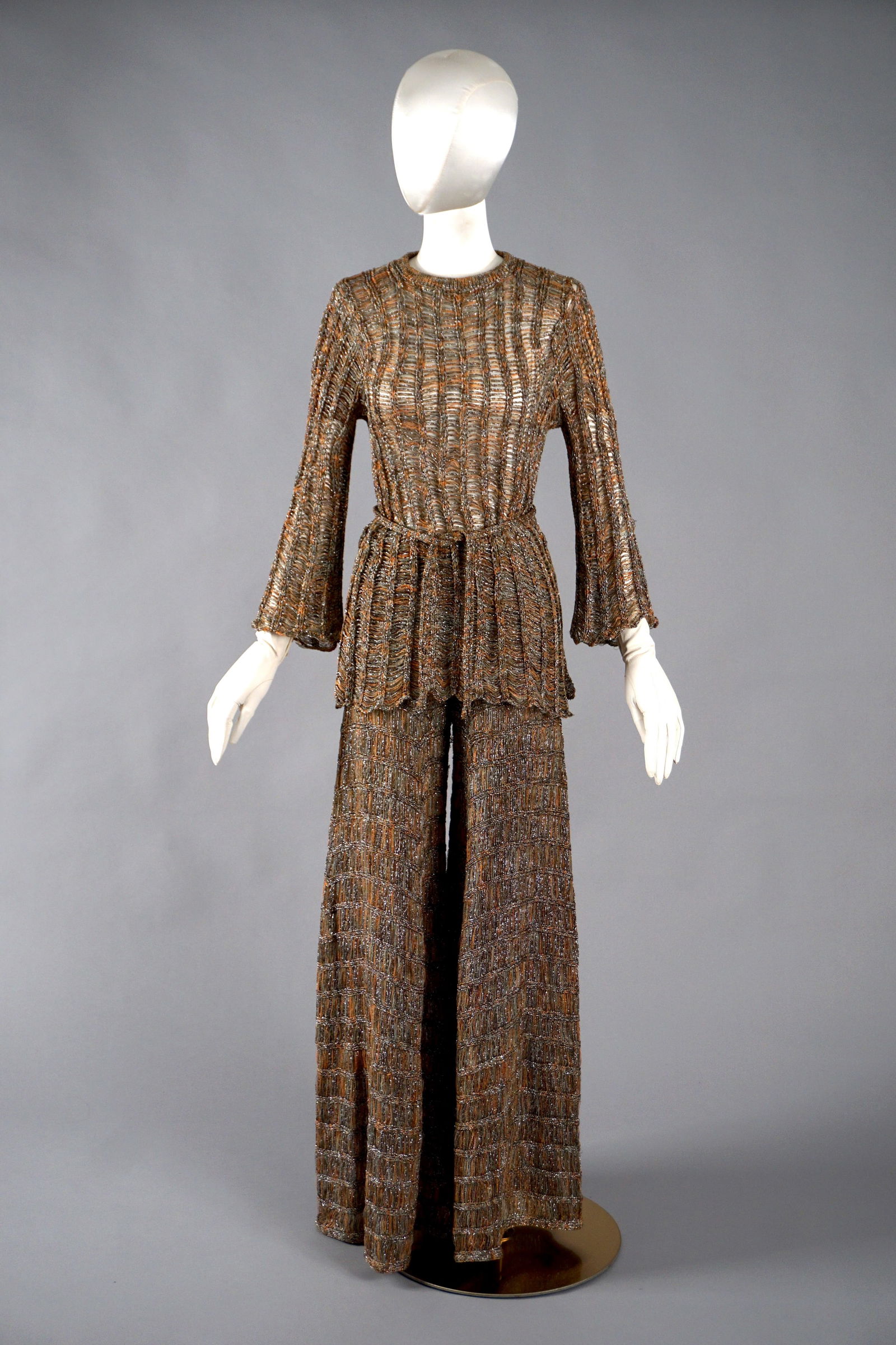1970s Mary Farrin London Metallic Knit Blouse & Pants Set: Vintage 1970s ensemble by Mary Farrin, comprising a long-sleeved blouse and matching wide-leg trousers, both crafted in a richly textured openwork knit. The fabric blends shimmering silver, copper, ol