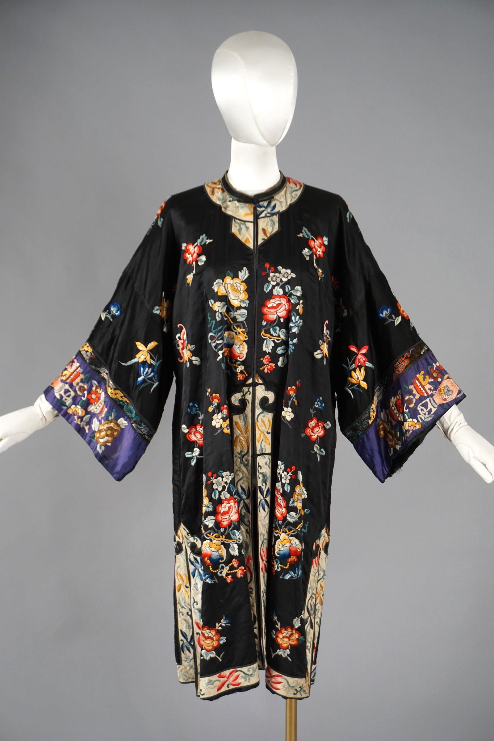 1920s Chinese Embroidered Silk Robe Polychrome Floral Vase Motifs: 20th century Chinese lady’s robe, circa 1920s, crafted from black silk and richly embroidered in vibrant silk floss. The design features multicolored peony, chrysanthemum, and lotus blossoms symboli