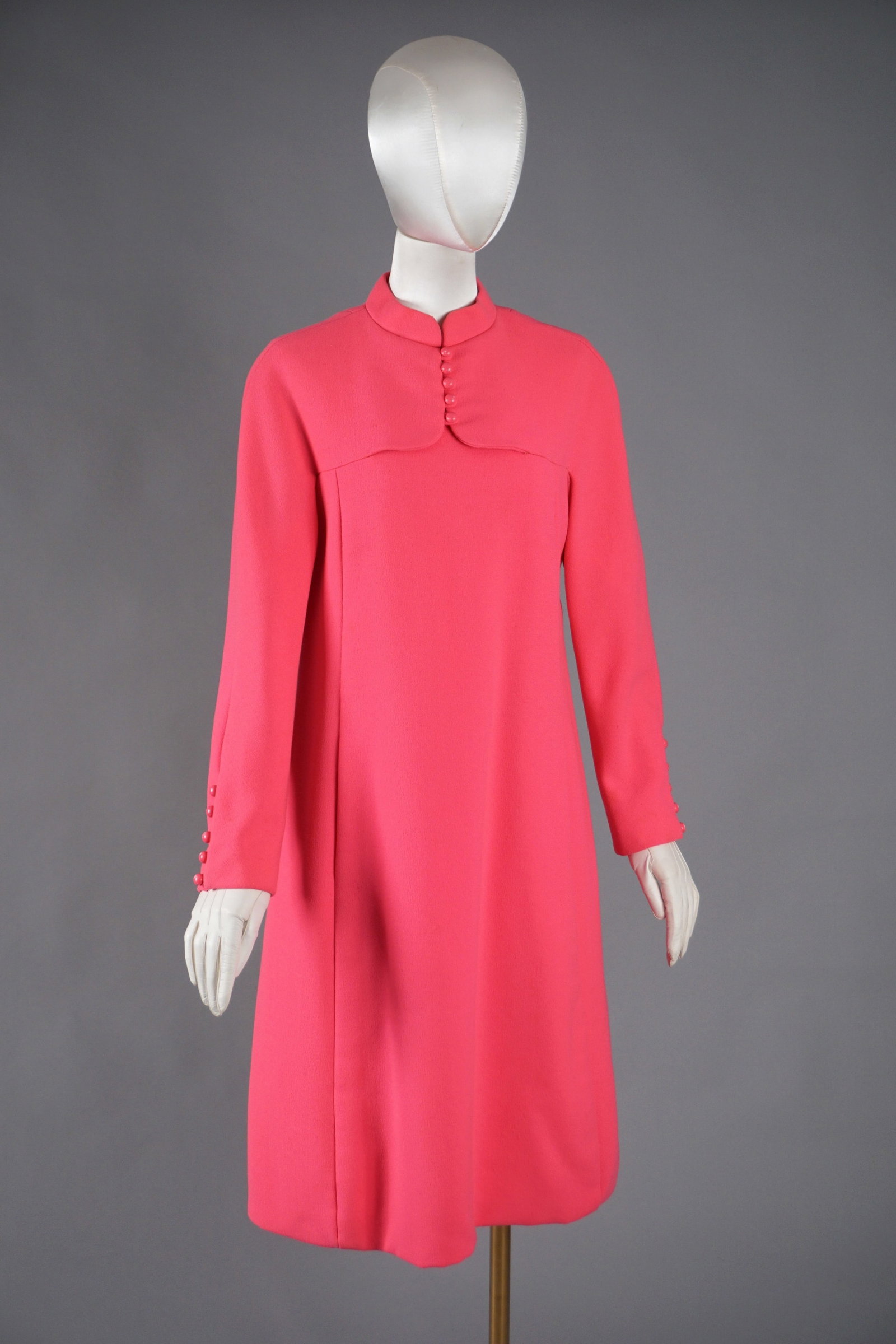 Vintage Geoffrey Beene Hot Pink Mod Dress, ca. 1960s: A 1960s Geoffrey Beene shift dress in vibrant hot pink wool blend, featuring a sculptural faux capelet detail at the front bodice, high neckline, and signature covered buttons at both front and cuffs.