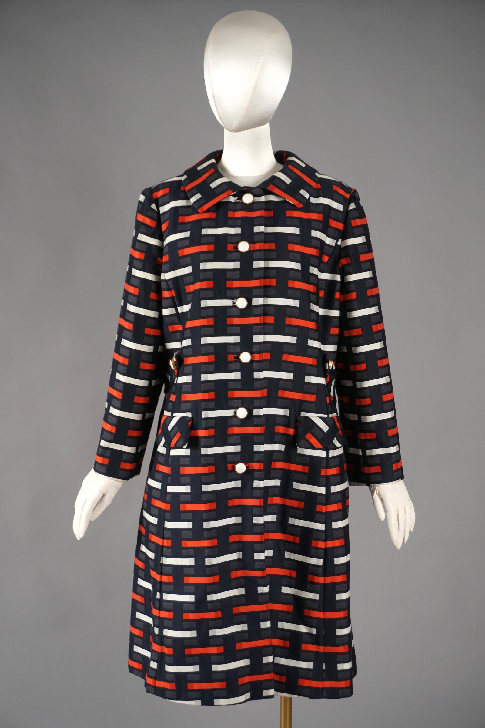 Vintage Saks Fifth Avenue Mod Coat Graphic Red-Navy Print: A 1960s mod coat from Saks Fifth Avenue, featuring a bold geometric block print in red, navy, ivory, and charcoal. The straight silhouette is accented by a matching belt detail at the back waist and c