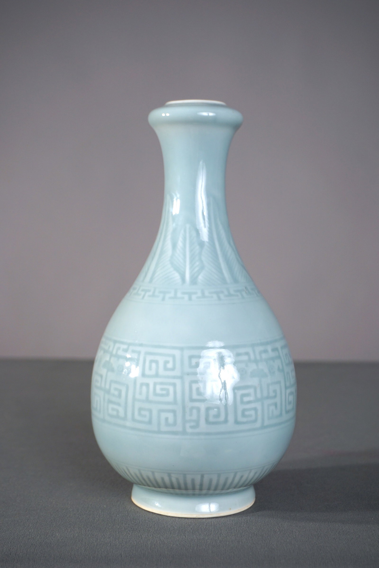 A Chinese Blue Celadon Porcelain Clair de Lune Vase, Qianlong Mark: The vase elegantly potted with a gently tapering bulbous body rising from a subtly splayed foot to a slender neck and terminating in a distinctly rounded garlic-head mouth. The porcelain body is metic