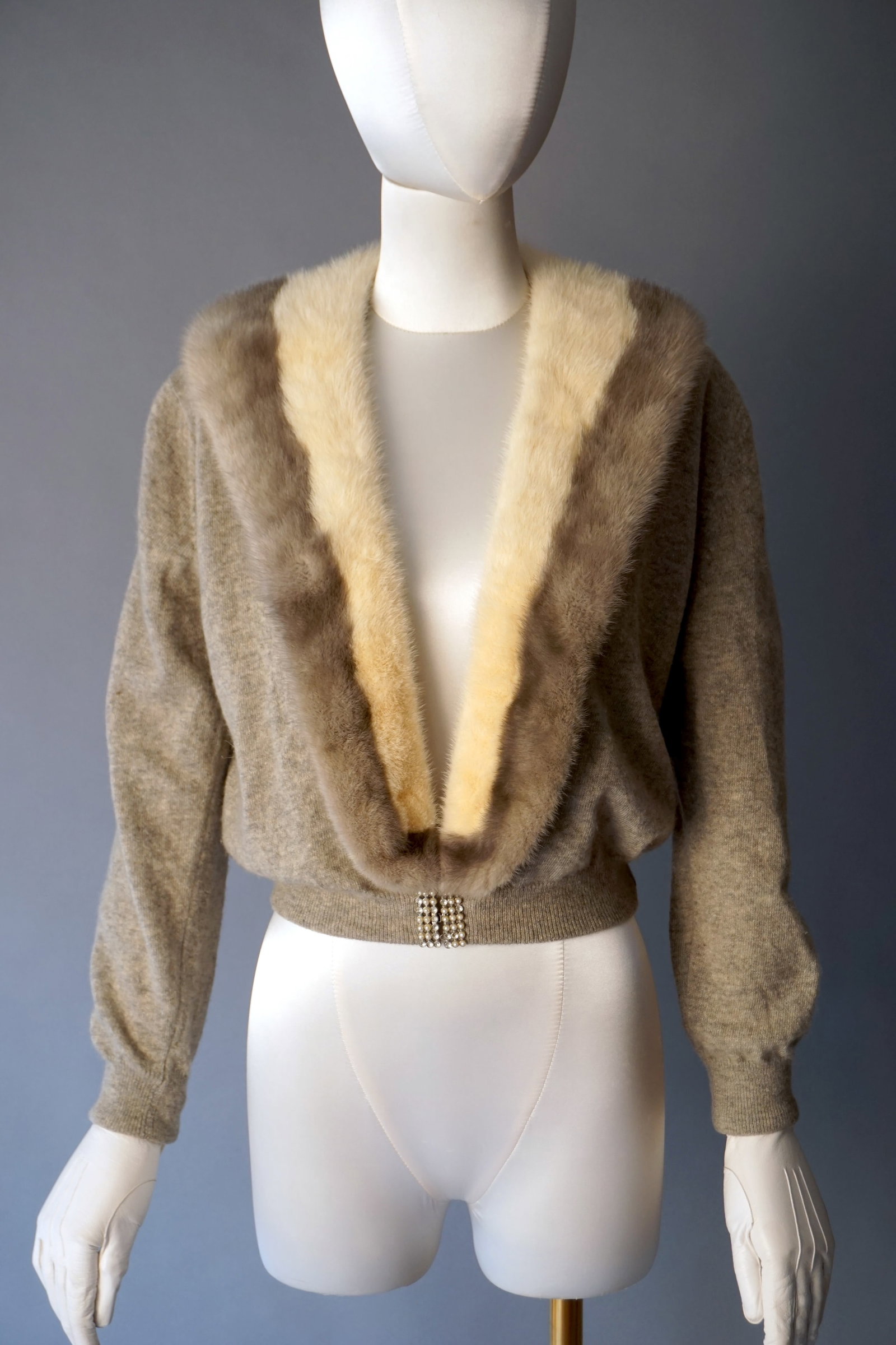 Vintage Cashmere Cardigan with Mink Collar & Rhinestone Clasp: Mid century cashmere cardigan in a soft heathered gray, featuring a striking multitone mink fur collar in cream and silver-gray, fully detachable with snap buttons. Secured by a rhinestone clasp at th