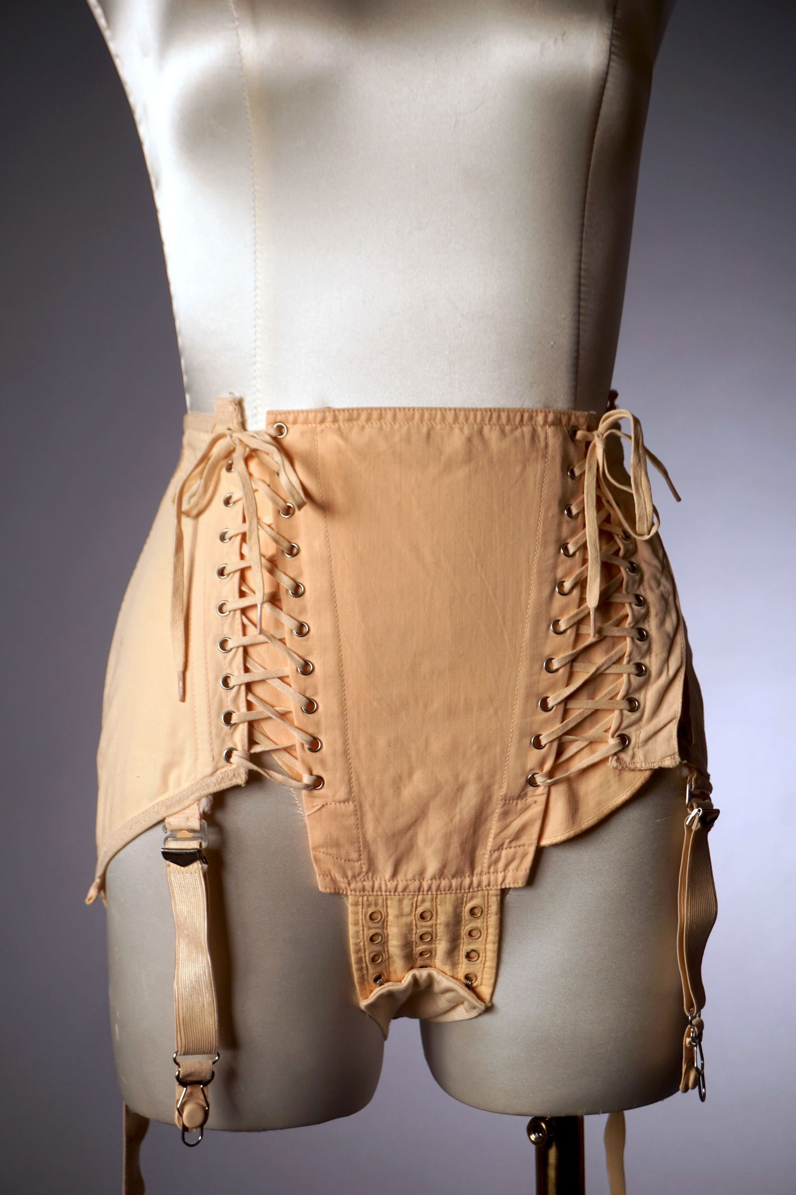 Vintage Pink Corset Girdle, Nu-Lift with Original Box, Mid Century: A mid century NuLift girdle corset in pale peach cotton, designed with adjustable lacing at the front. The piece includes attached garters, a detachable crotch section, and the original instruction sh