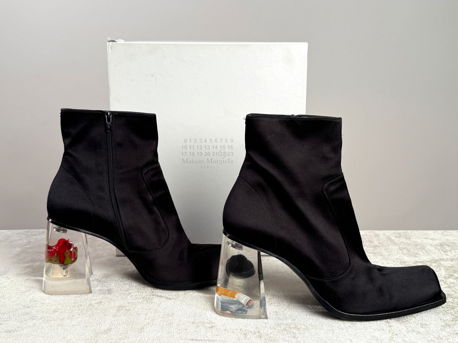 Maison Margiela Lucite Rose Cigarette Heels Ankle Boots Size 9: Collectible Maison Margiela black satin squared toe ankle boots made in Italy, featuring the house’s iconic transparent acrylic heel encasing a sculptural rose and cigarette motif. Designed with a s