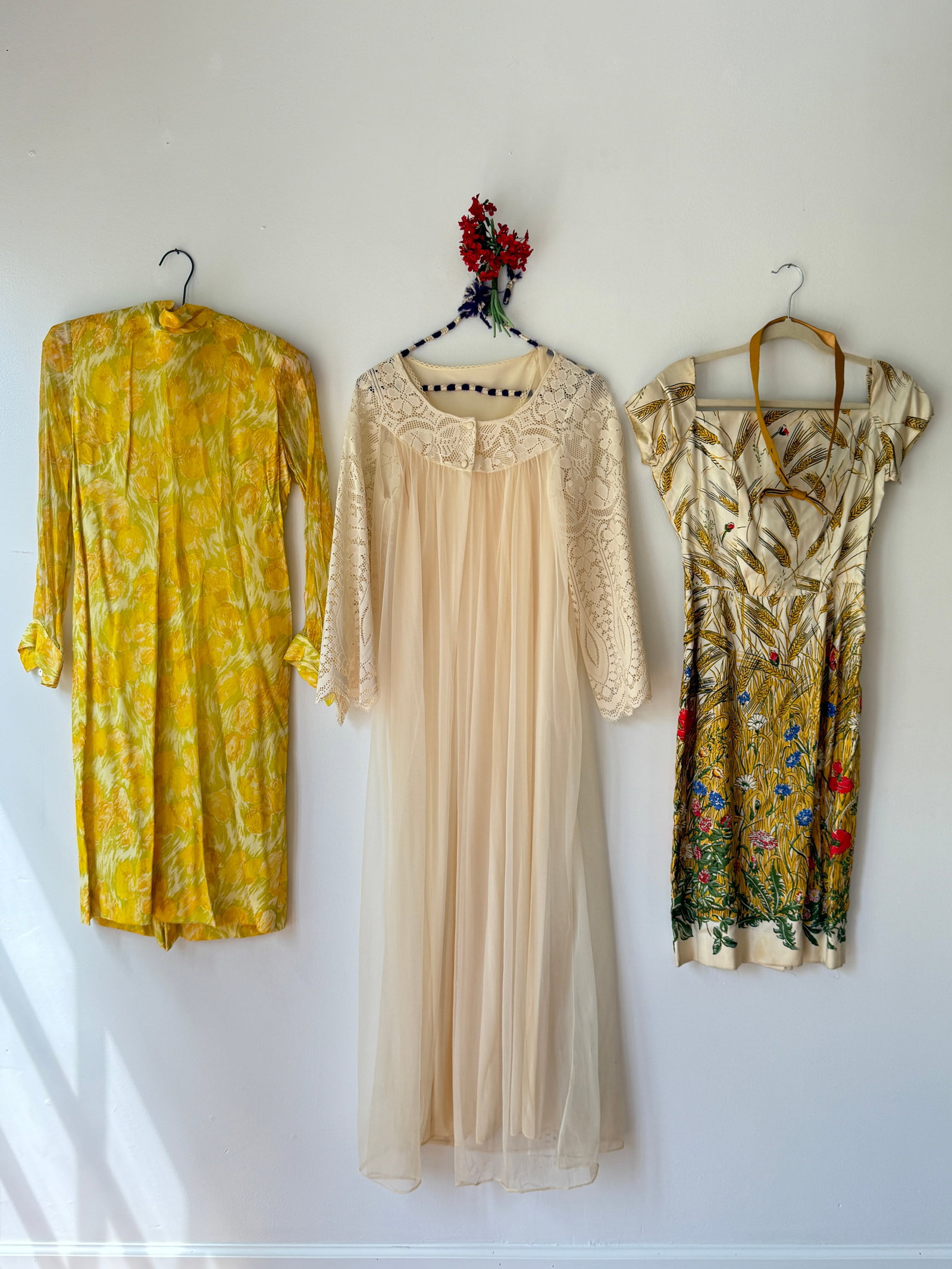 Lot of Three Vintage Mid Century Women's Dresses and Lingerie Robe: Included in this lot is a 1960s long sleeved dress in a yellow abstract floral print on a light, sheer fabric. The second is a 1950s novelty dress with wheat and wildflower botanical motif w/ red popp