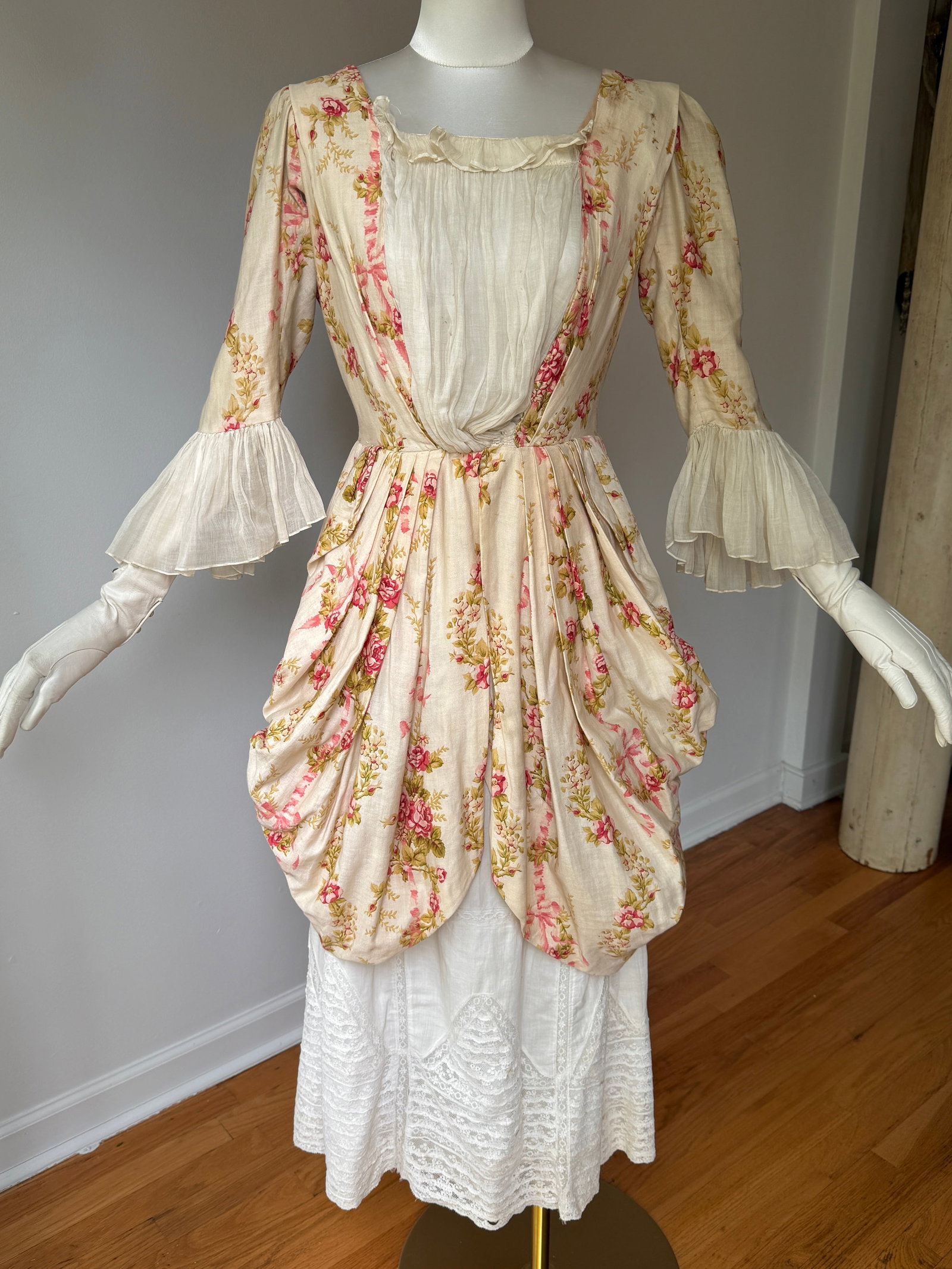 Antique Pink Floral Robe à la Polonaise Cotton Dress with Lace Under Skirt: Antique Victorian turn of the century Robe à la Polonaise style dress with lace trimmed under skirt. The dress is in a cream colored soft cotton base adorned with a romantic, all over pink rose and g