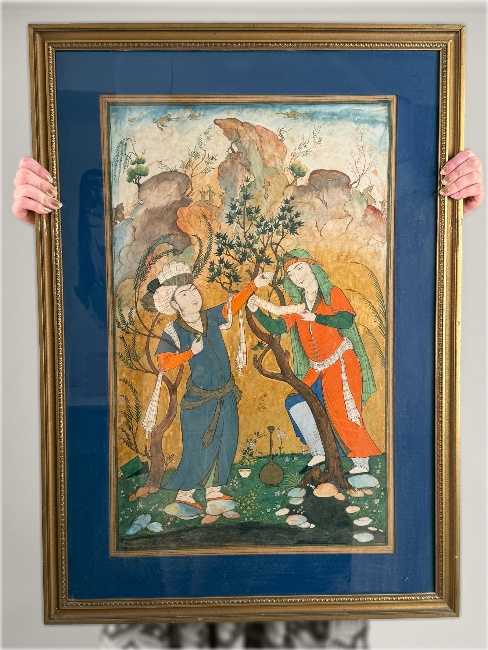 A Monumental Safavid Revival Persian Miniature Painting: Courtly Figures in a Rocky Landscape: Persian, Isfahan School, Pahlavi Era (circa Mid-20th Century, Manner of the Mirza Aqa Emami Workshop)This monumental gouache, ink, and gold on paperboard composition depicts two idealized youths in fi