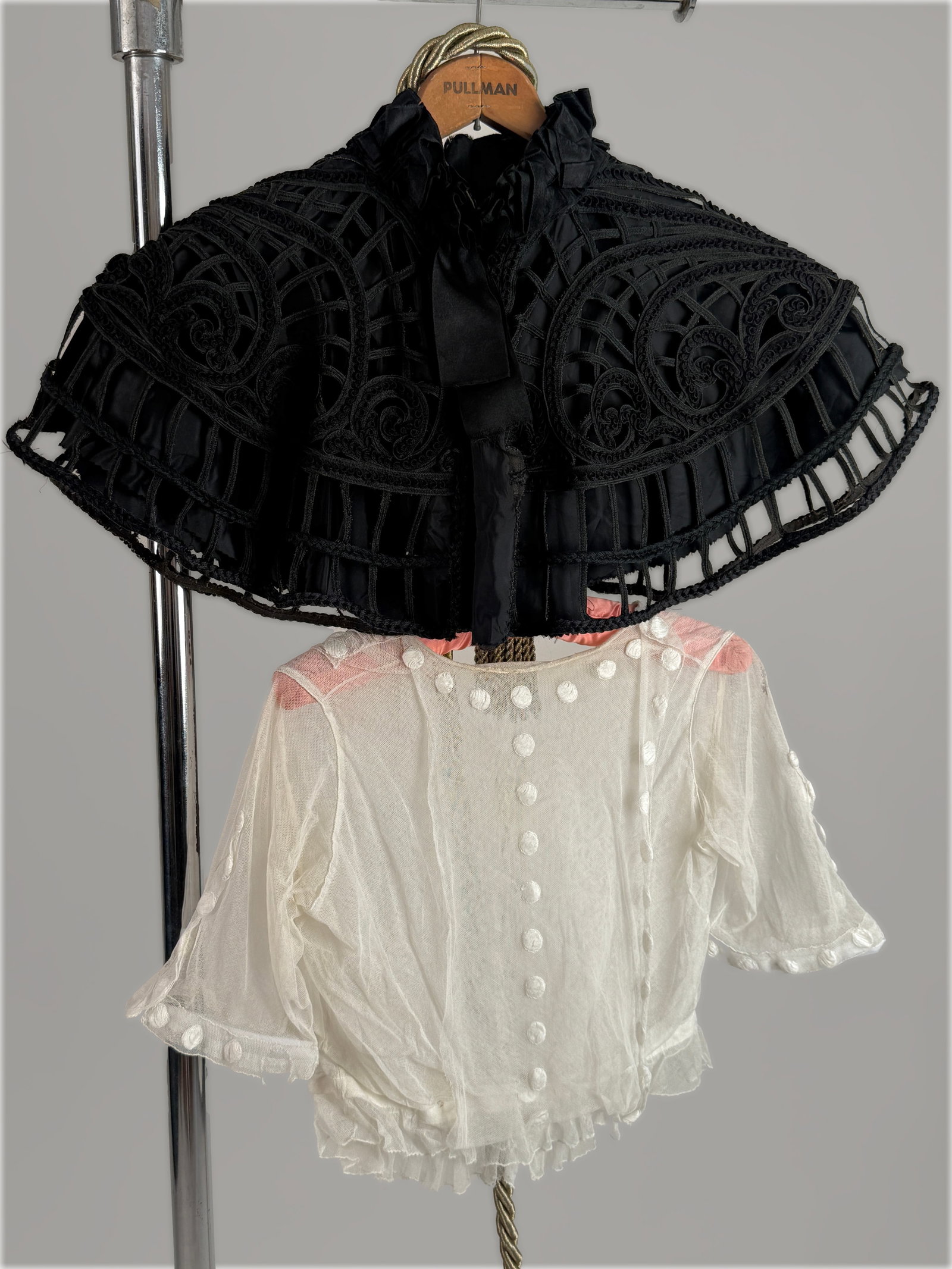 Lot of (2) Antique 1890s Edwardian Garments: Black Lace Capelet & White Dot Blouse: Antique Victorian black tape lace capelet with openwork geometric panels, braided trim and ruffled collar trim and antique white semi sheer cotton blouse adorned with allover raised Swiss dot motifs. 