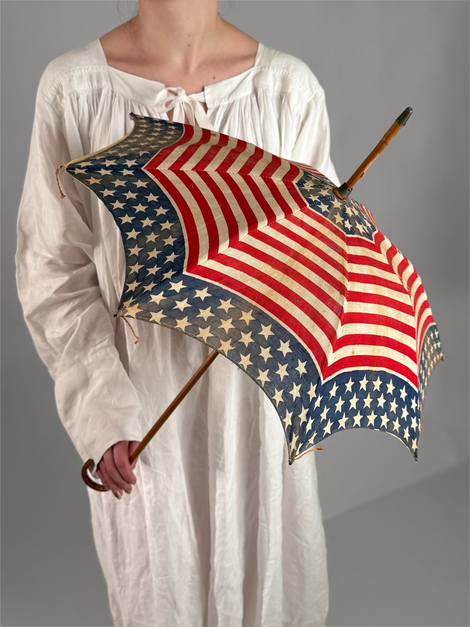 Antique American Flag Parade Parasol Umbrella 1900 1920s: Rare antique parasol styled after the United States flag. The fabric canopy showcases alternating sections of bold red and white stripes paired with a blue field of white stars, arranged in a radial p