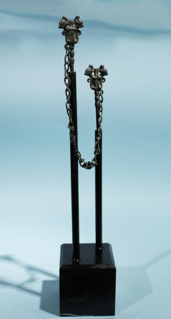 PAIR OF LURISTAN BRONZE PINS WITH FELINES: A pair of ancient Luristan bronze pins, joined by a later metal link chain. A pair of heraldic felines decorates the top of each pin. Ca. 1500 - 800 BC. Height of tallest pin: 4 1/4 in. (10.8 cm.). Fo