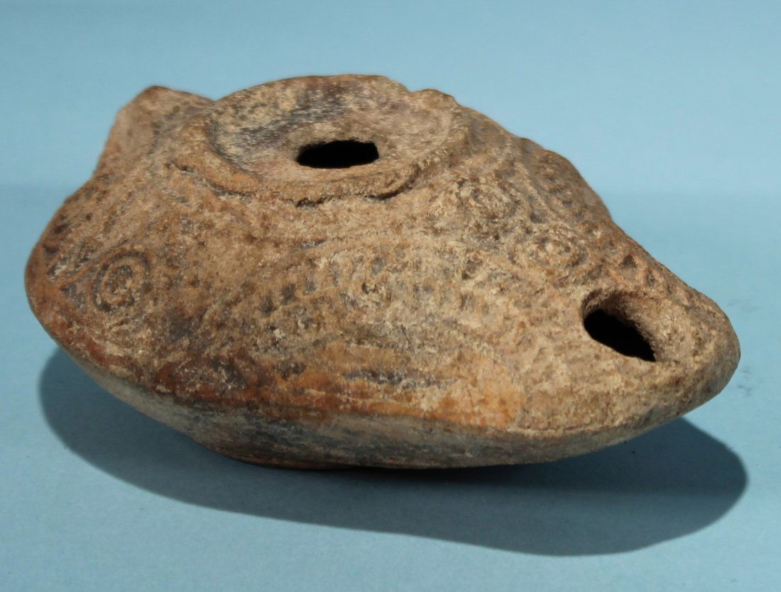JUDEAN OIL LAMP: An ancient Judaean pottery oil lamp with raised geometric and vegetal designs on the surface. Ca. 4th century AD. Length: 3 3/4 in. (9.5 cm.). Formerly in a Florida private collection.