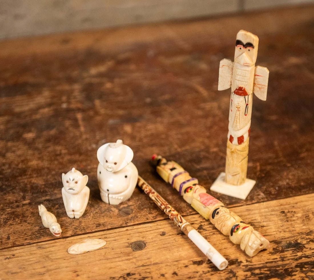 ALASKAN NATIVE CARVED ART ASSORTMENT: An assortment of Alaskan carved art including three bone totems, a seal and whale carved out of stone, and two Billiken stone sculptures. Size 6.5"H 1.75"W 1.5" D Condition Various.