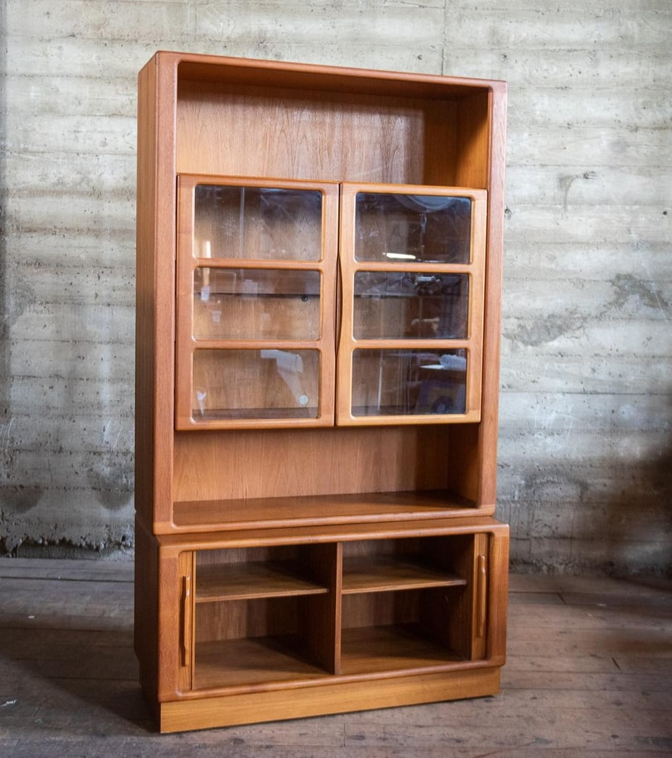 DANISH DISPLAY CABINET BY NIELS BACH FOR DYRLUND, 1960S: Two piece display or storage cabinet by Niels Bach for Dyrlund, made in Denmark circa 1960s. The bottom cabinet is on casters and features tambour cabinet doors. The top piece has cabinet storage and