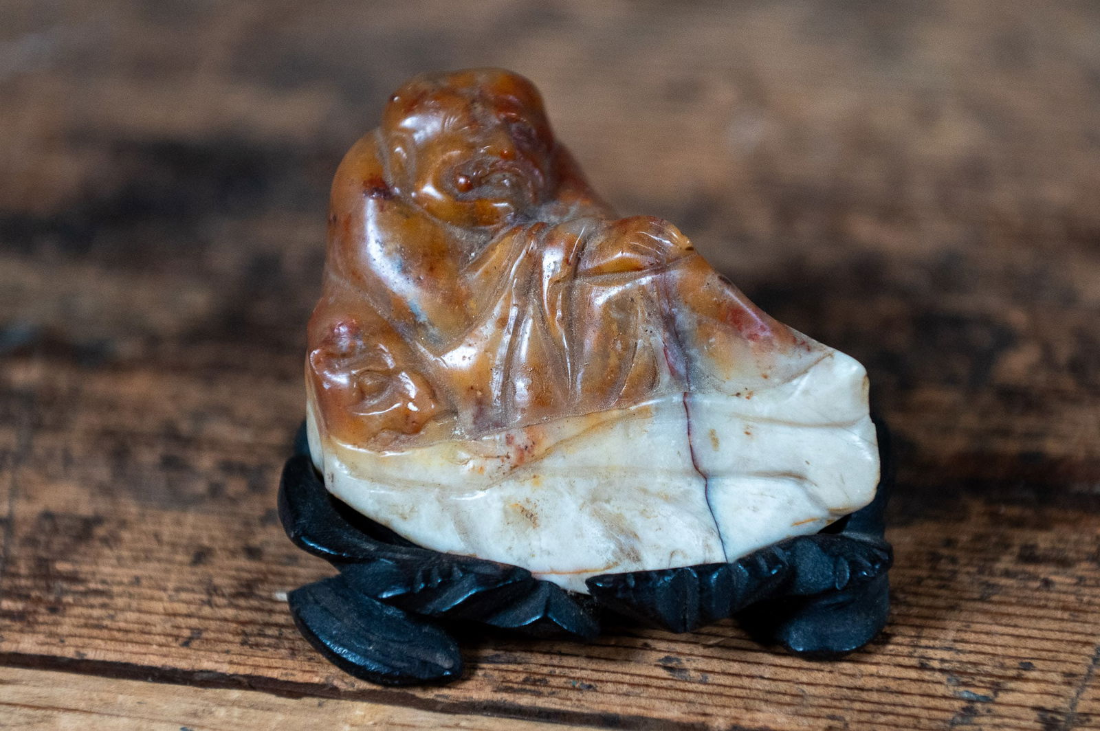 CARVED SOAPSTONE BUDDHA ON STAND: This lot features an antique carved Soapstone Buddha on wood stand.
