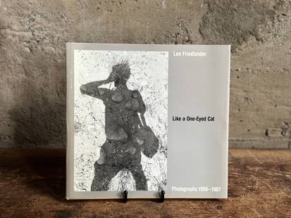 LEE FRIEDLANDER, "LIKE A ONE-EYED CAT" SIGNED BOOK: "Like a One-Eyed Cat" a hand-signed hardcover book by listed photographer, Lee Friedlander. Lee Friedlander is an American photographer and artist. In the 1960s and 1970s, Friedlander evolved an influ