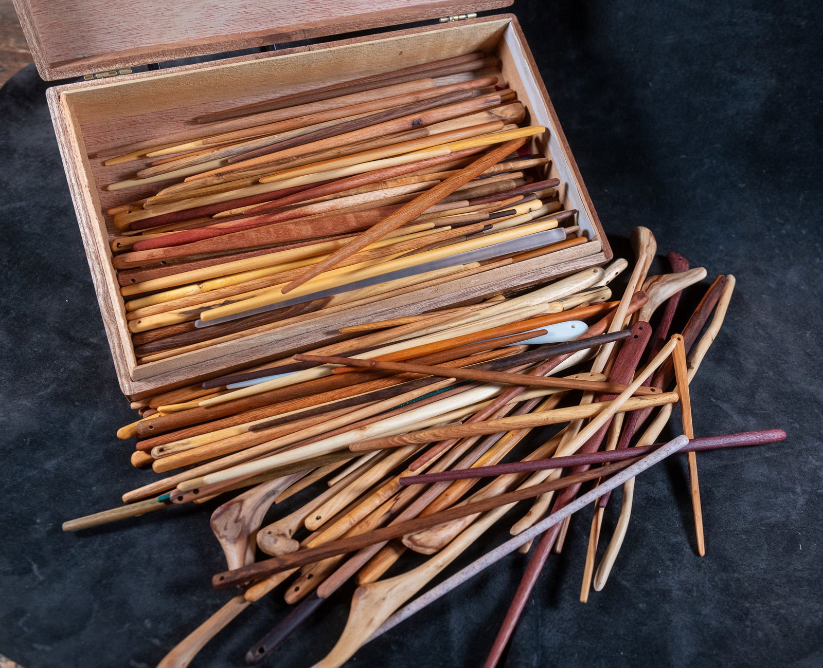 BOX OF WOOD ITEMS #5, STICKS WITH HOLES, LARRY PETERSON: A cigar box full of sticks with holes, hand-crafted out of exotic woods from around the world. Artisan made by Oregon woodworker, Larry Peterson.