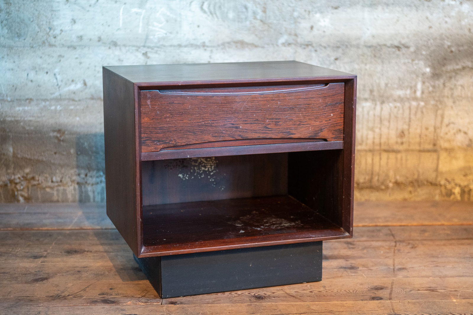 ROSEWOOD BEDSIDE TABLE BY DYRLUND: Rosewood bedside table by Dyrlund, circa 1960's. Compact size with dovetailed drawer and open storage cubby. Maker mark shown inside drawer. Dyrlund was founded in 1960 and is one of the top manufactu