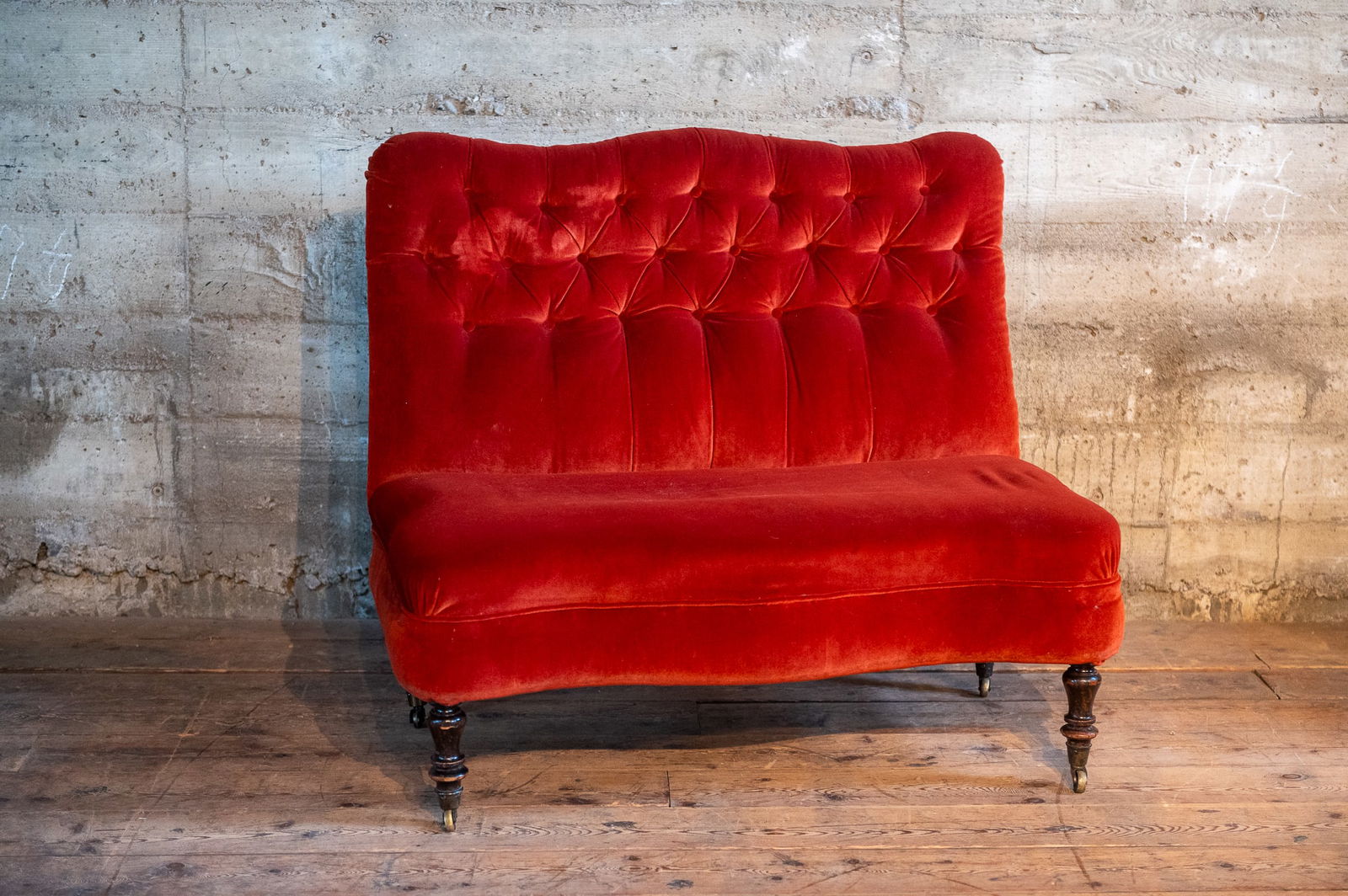 RED VELVET HORSEHAIR LOVESEAT, EARLY 20TH C.: A red velvet upholstered loveseat, with a horsehair stuffed spring seat. Ornately carved wooden legs on casters. Circa early 20th Century and originating from the United Kingdom. Upholstery is in good