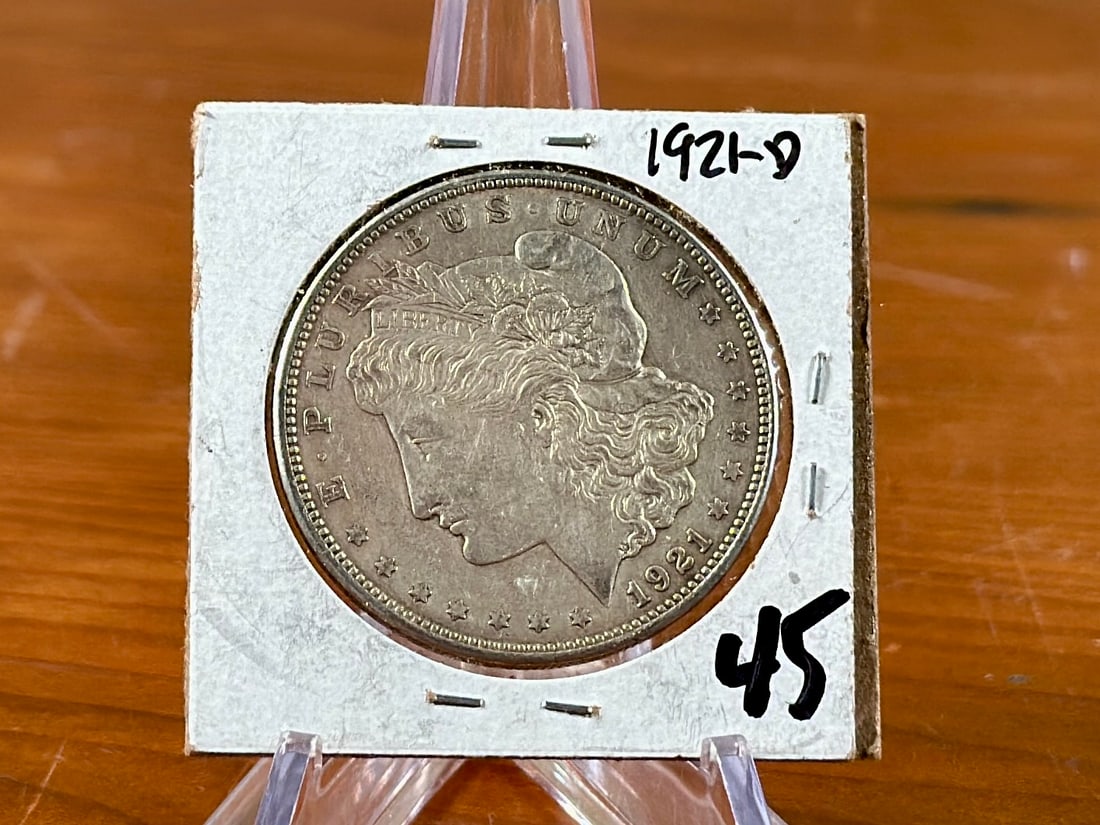 1921-D MORGAN DOLLAR: This lot features a 1921-D Morgan Dollar, kept in a protective sleeve. The Morgan silver dollar, designed by George T. Morgan, was minted from 1878 to 1904, and again in 1921, becoming a popular coin 
