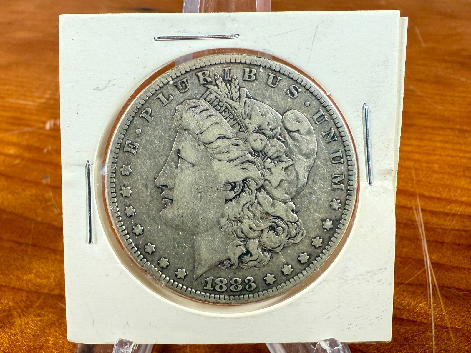 1883 MORGAN DOLLAR: This lot features a 1883 Morgan Silver Dollar. The Morgan dollar, also known as the Morgan silver dollar, was minted in the United States from 1878 to 1904 and again in 1921. Designed by Mint Chief En