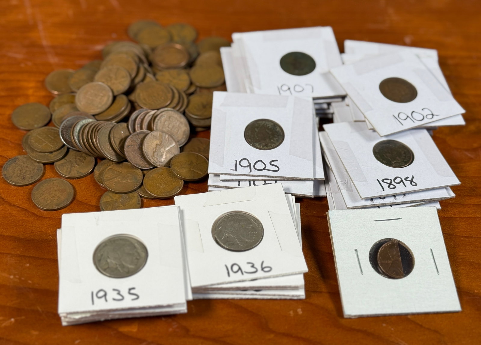 INDIAN HEAD PENNIES, WHEAT PENNIES, & BUFFALO NICKELS: This lot features a large assortment of Indian Head Pennies, Wheat Pennies, & Buffalo Nickels from various years. Many of the coins are in protective slips. There is also an industrial cut half-pe