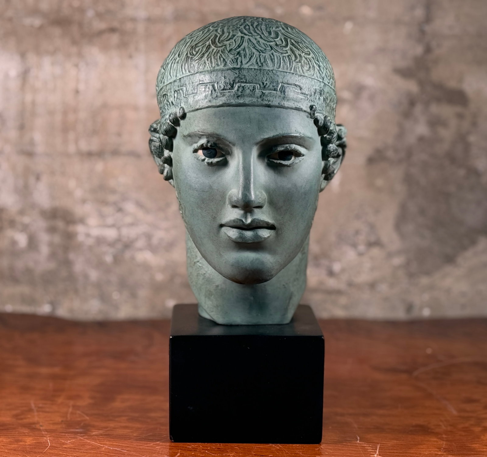 PATINATED PLASTER HEAD OF THE CHARIOTEER OF DELPHI: This lot features a patinated plaster head of the Charioteer of Delphi circa 1962 with maker stamp present as shown in photos. This sculpture measures, 15'' H x 6'' W x 8.5'' D. The Charioteer of Delp