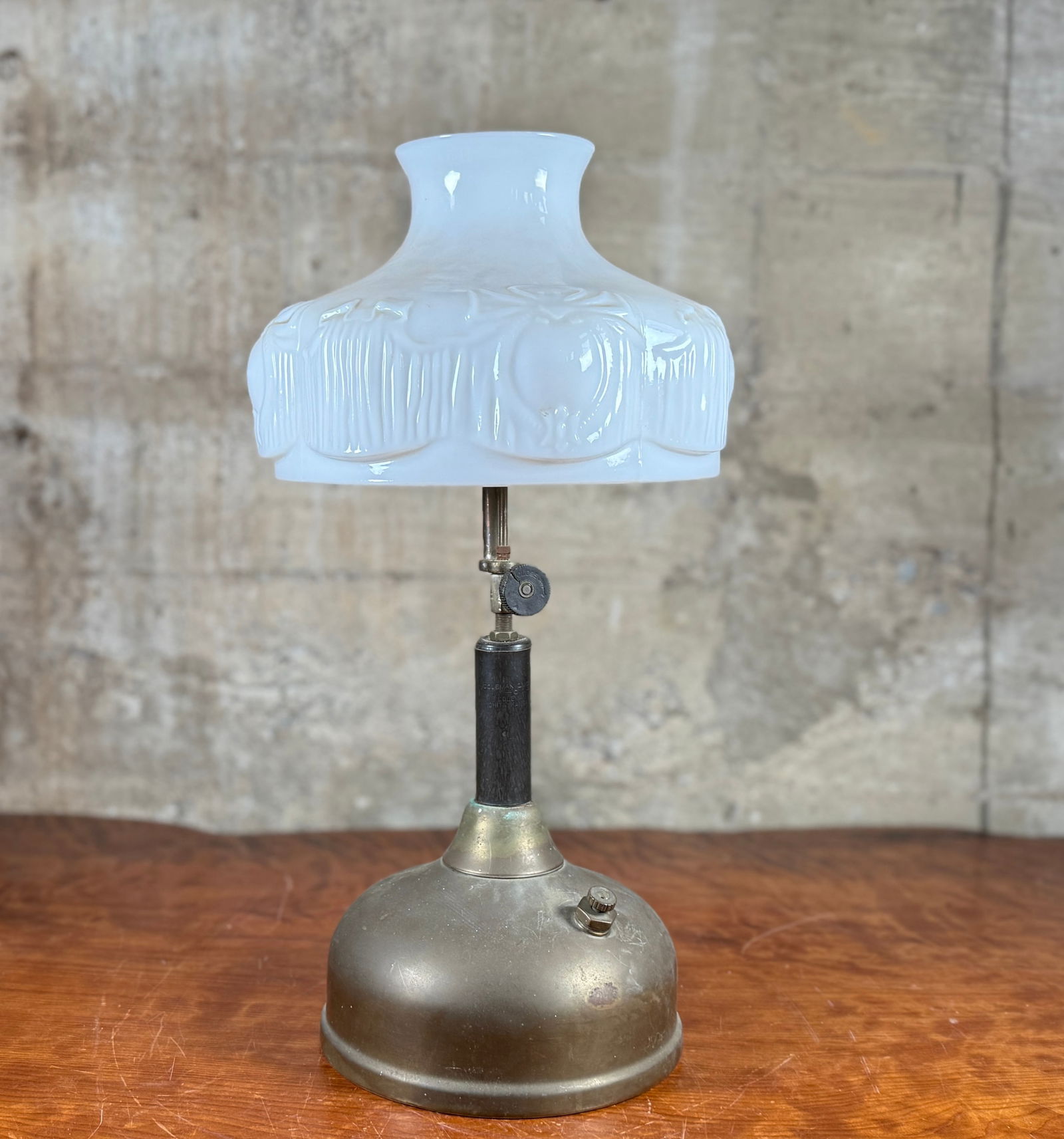 COLEMAN QUICK-LITE TABLE LAMP: This lot features an antique Coleman Quick-Lite table lamp, circa 1920s with a pressurized metal fount, a column, and a beautiful milk glass shade. This piece measures, 20'' H x 10'' W x 10'' D.