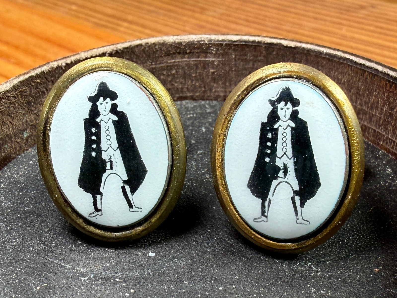 CANTERBURY, 'RISQUE CUFFLINKS': This lot features a pair of "risque cufflinks", manufactured by Canterbury from 1960-1969. They feature a brass frame and ceramic insets. The cufflinks come in the original Canterbury