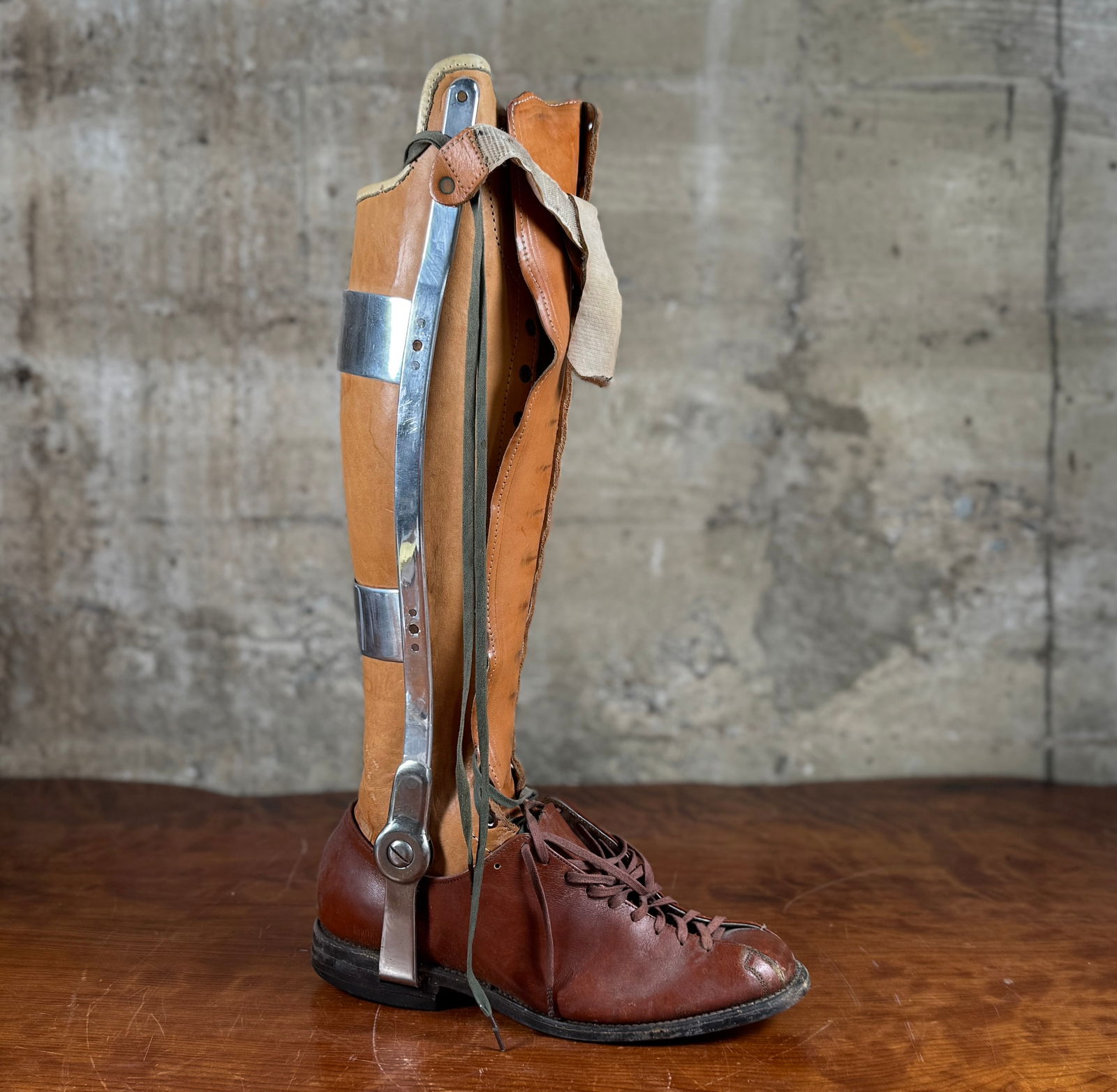 EARLY 20TH CENTURY ORTHOPEDIC LEG BRACE: This lot features an antique orthopedic leg brace, specifically a metal and leather KAFO (Knee-Ankle-Foot Orthosis) from the early-to-mid 20th century. Constructed from leather, metal bracing, and a