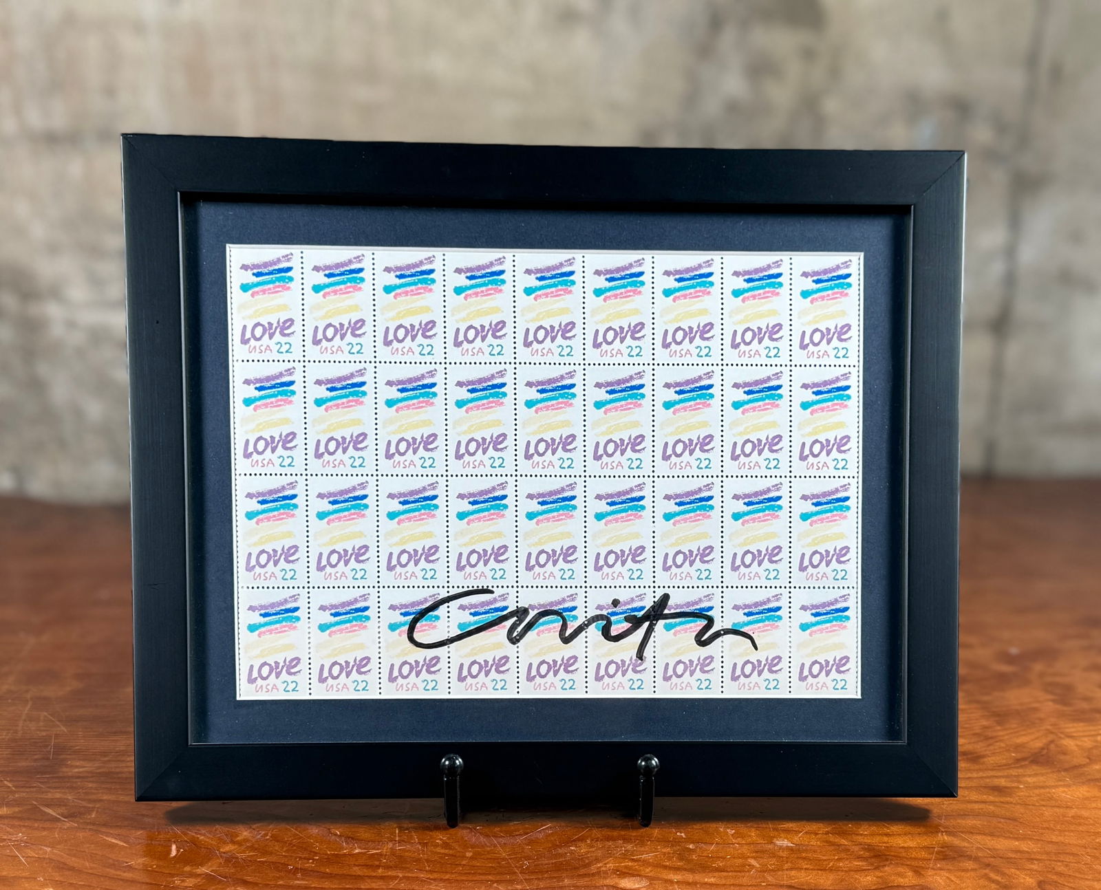 CORITA KENT, SIGNED STAMP SHEET: This lot features a professionally framed sheet of 1985 "Love" postage stamps designed by Sister Corita and hand-signed by Kent. This piece measures in frame, 9'' H x 12'' W. Corita Kent,