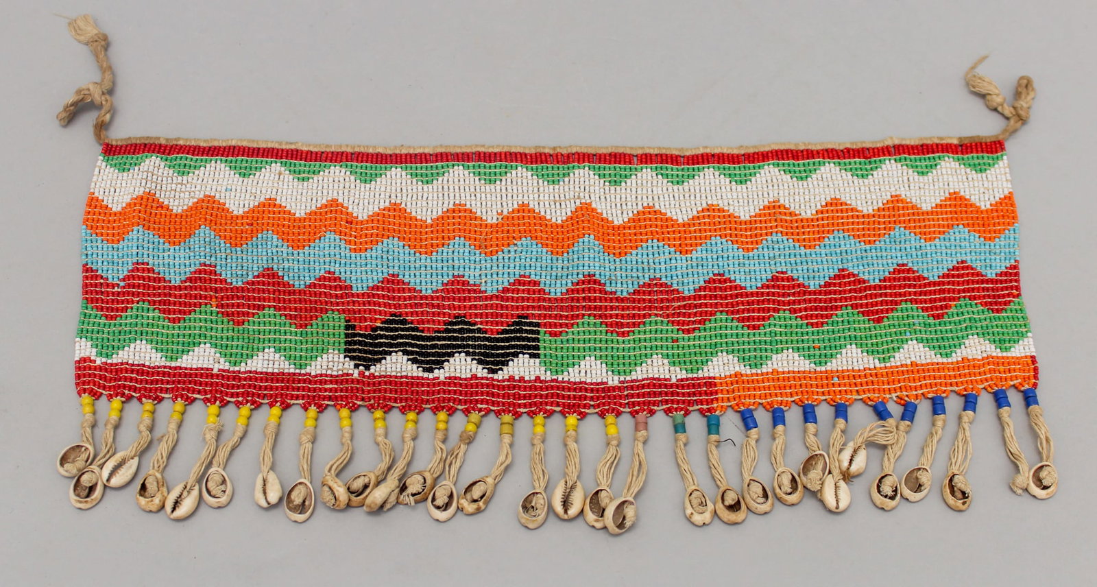 A Beaded Cashe Sexe, Kirdi peoples, North-Western Cameroon, West Africa: A beaded cashe sexe, Kirdi peoples, North-Western Cameroon, West Africa, mid-20th century. Approximate size, 8"H (including tassels) x 17.5"W. PROVENANCE: From the estate of Dr. Philip Gould, New York