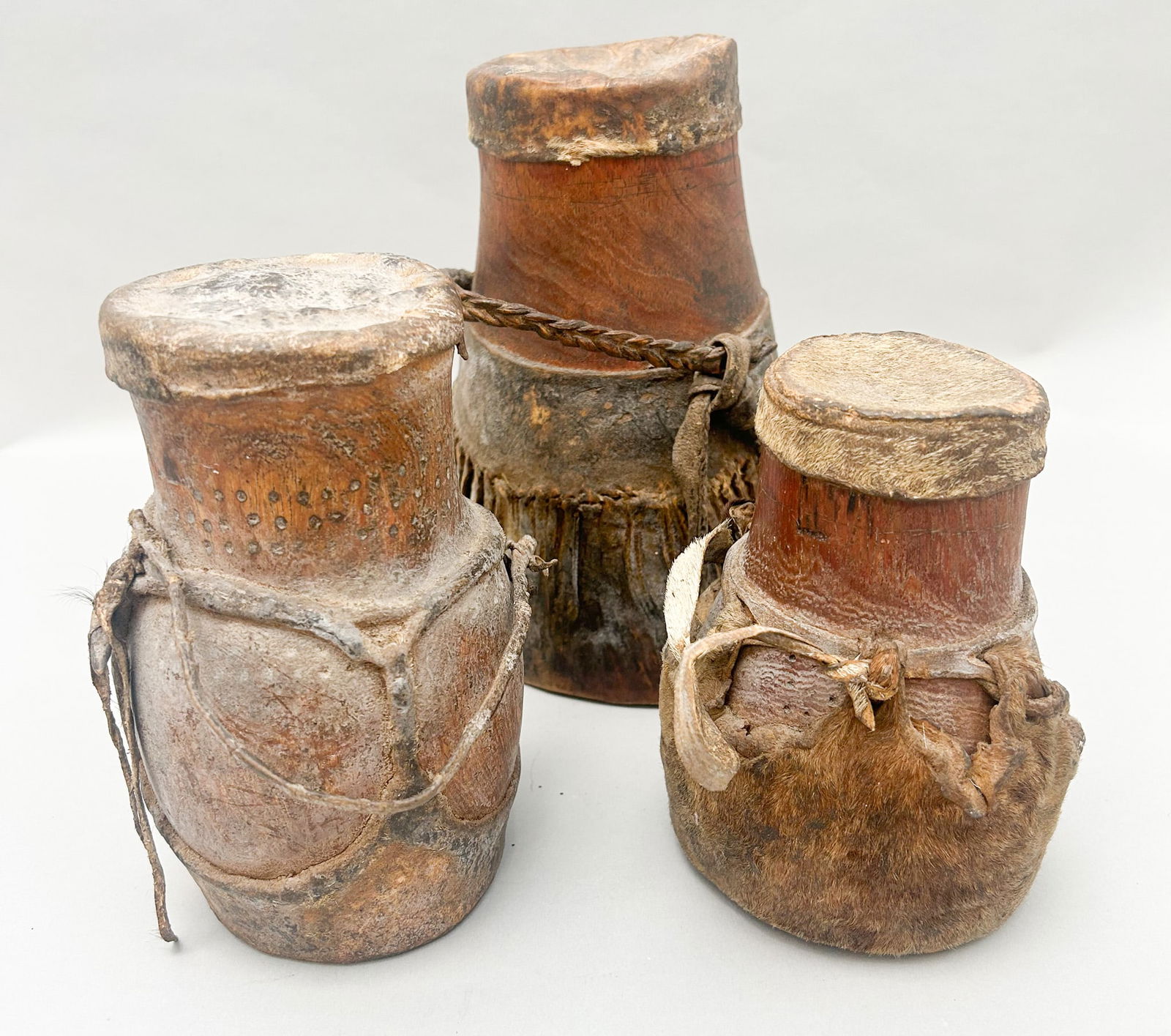 A Group of (3) Vintage Wooden and Leather Turkana Honey-Milk Pot: A group of (3) vintage wooden and leather Turkana honey-milk pot, largest pot 8.75"h x 5"w x 6 "d and smallest pot 6"h x 4"w x 3.5 "d