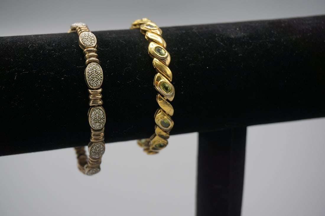 Lot of 2 - Sterling Silver Gold Tone Tennis Bracelets: Lot of 2 - Sterling Silver Gold Color Tennis Bracelets. Bracelet 1: Gold color with green stones. Bracelet 2- Silver color with rhinestones. Wgt: 33 gr. All weights are approximate