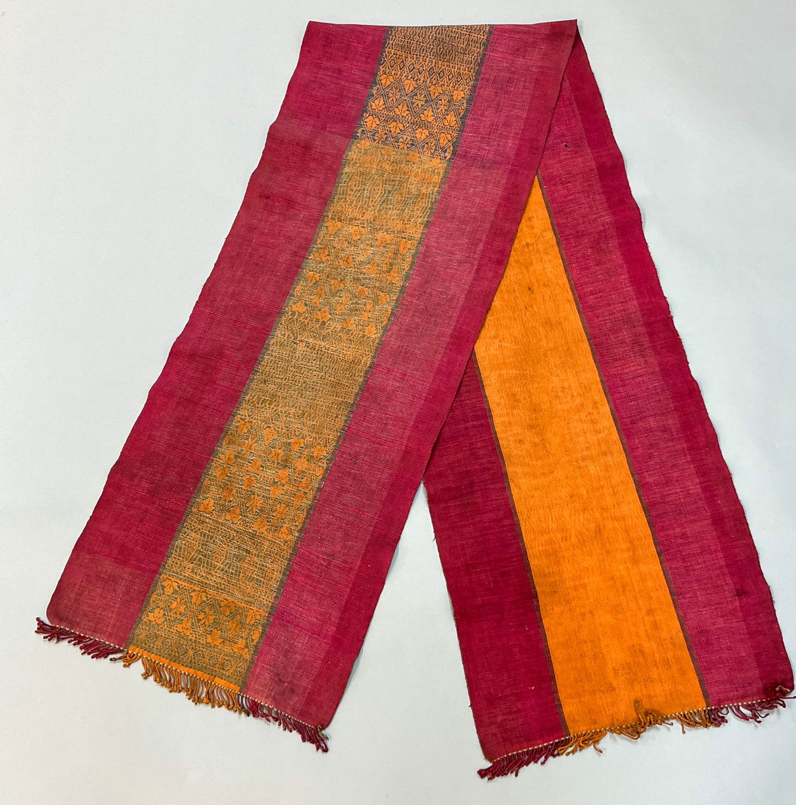 Ubon Ratchathani, Thailand, Vintage Woven Cotton Men's Sash: Ubon Ratchathani, Thailand, vintage woven cotton men's sash, raspberry ground with orange and grey silk tread embroidery pattern, 71"l x 15" w Provenance: From the state of Dr. Philip Gould , New York