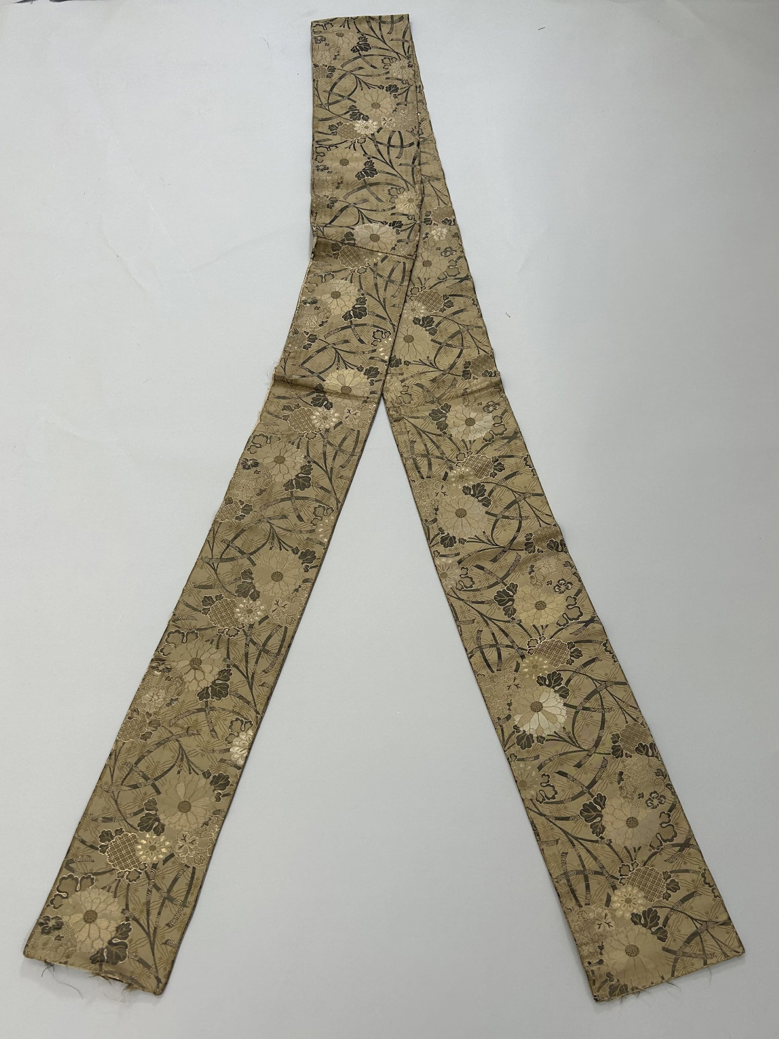 Japanese Gold Colored Silk Obi: Japanese Gold Colored Silk Obi with Flower Pattern, 117"l x 6"w Provenance: From the estate of Dr. Philip Gould , New York