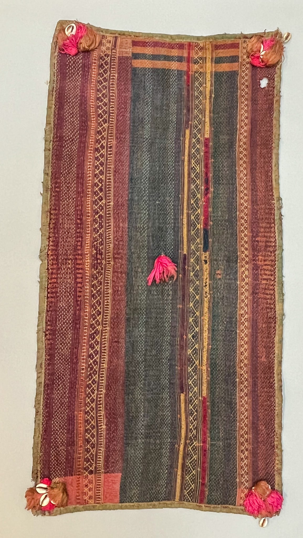 Orissa, India, Kantha Quilt: Orissa, India, Kantha quilt, green, rust color with stitched patterns, cowrie shells and tassels, 34"l x 17"w Provenance: From the estate of Dr. Philip Gould , New York