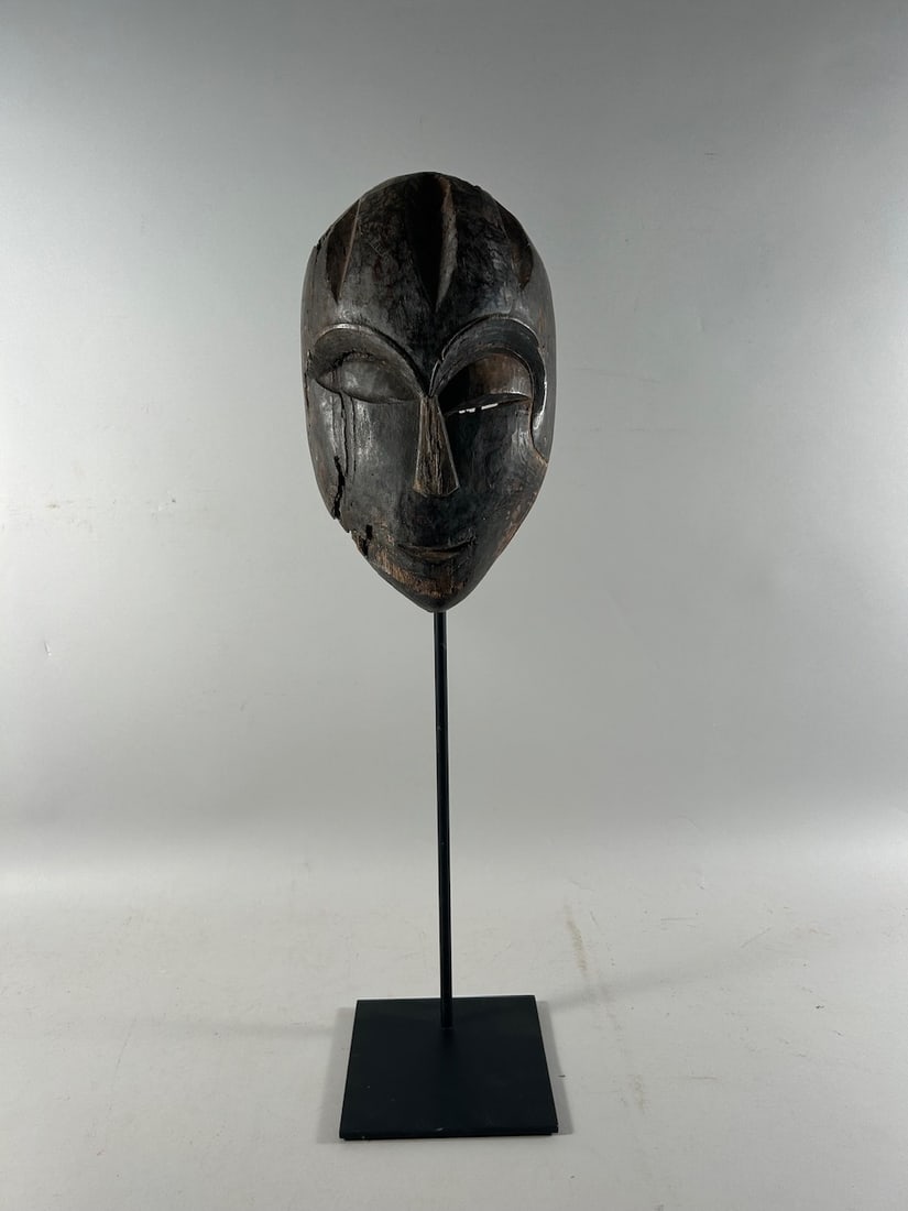 Idoma Style Mask: Idoma style carved wood mask, Nigeria, West Africa. Dimensions (approx.) : 11.5" x 6.75" x 3.5"NOTE: Metal stand NOT included in the lot. PROVENANCE:From the estate of Professor Philip Gould, New York