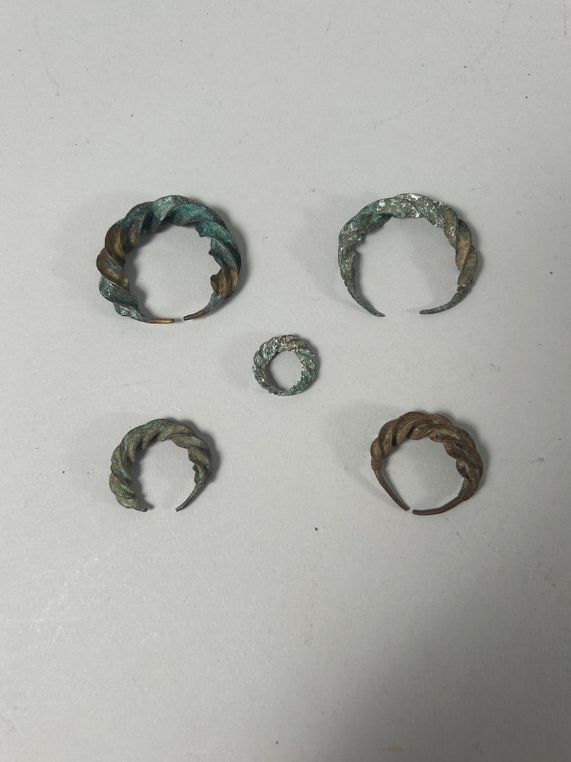 African Copper Alloy Earrings (5): Five (5) African copper alloy earrings. Dimensions (approx.): 1.75" diameter (largest) to 0.75" (smallest) PROVENANCE:From the estate of Professor Philip Gould, New York