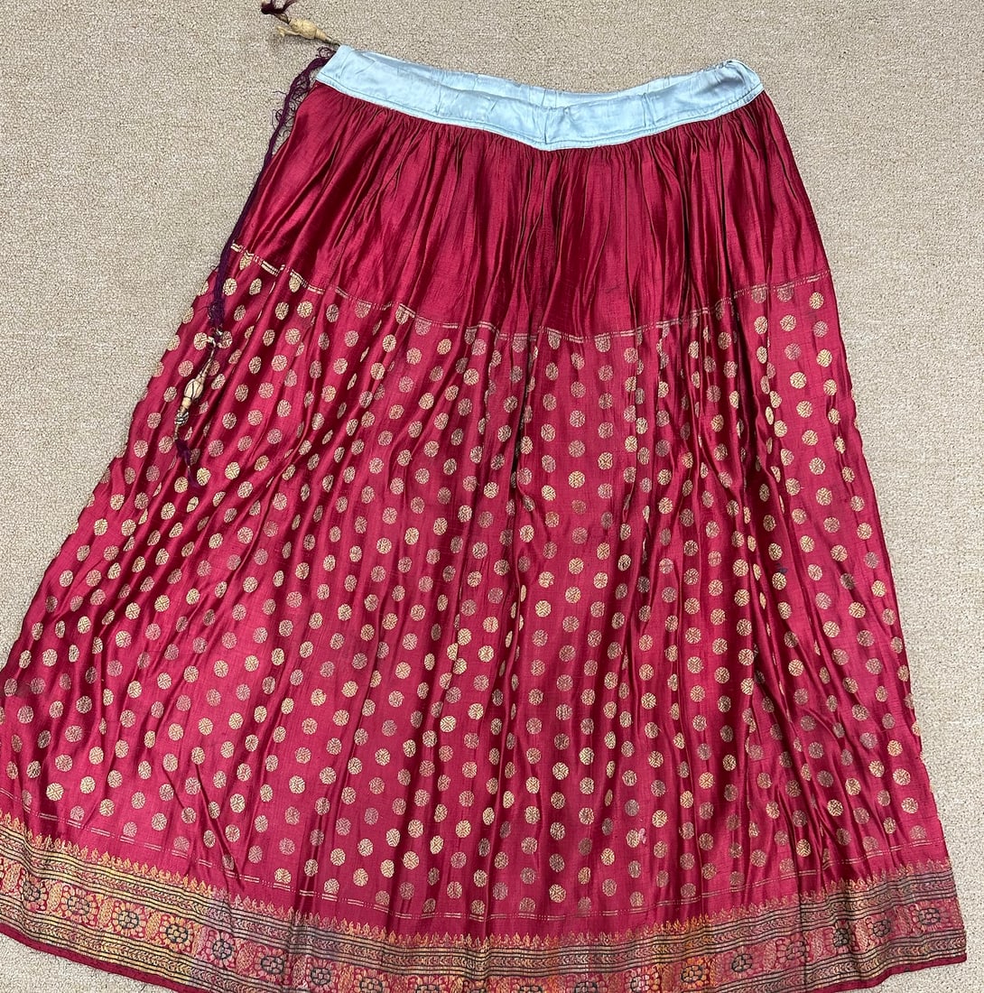 Traditional Indian Gujarati Ghadra Silk Skirt: Traditional Indian silk skirt with deep red and gold accents. Polka dot pattern fabric with pleats and a blue inner lining. D: 18" W x 34" L.