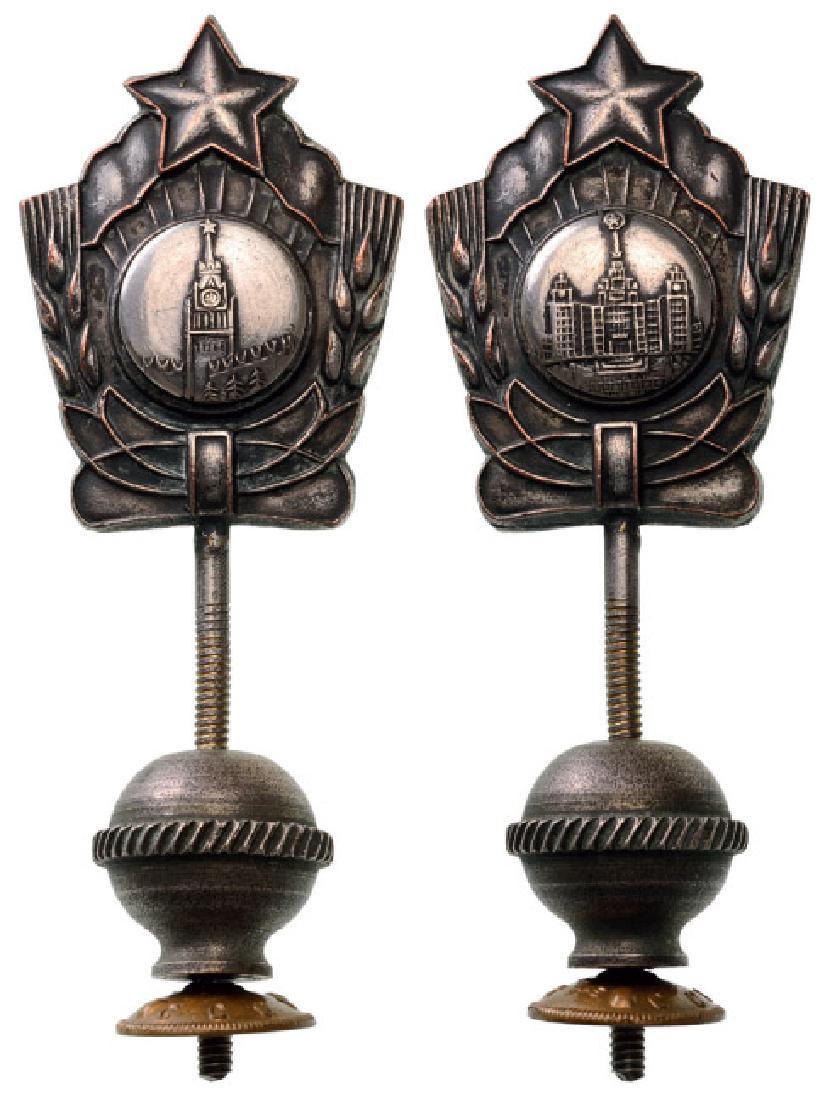 COMMUNIST PROPAGANDA SOUVENIR, CIRCA 1950: Stopper showing Soviet Architecture on both sides, 65x35 mm, silvered bronze, with threaded stem. I