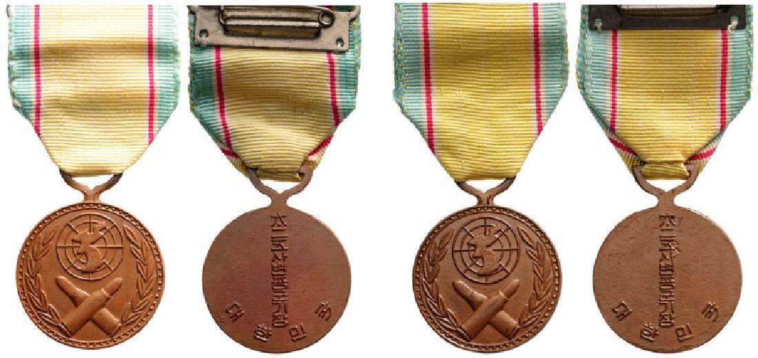 Lot of 2 War Service Medal, instituted in 1950: Breast Badge, Bronze, 32 mm, Korean inscriptions on back, original ribbons and attachment bars. (2) I