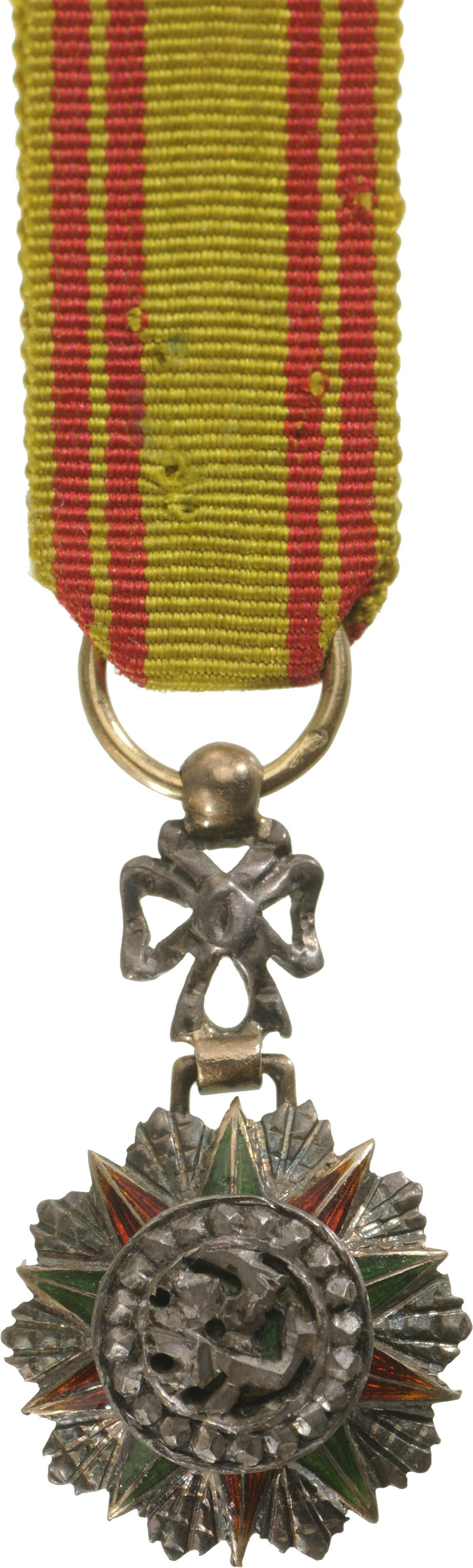 ORDER OF NICHAN AL IFTIKHAR: Knight's Cross Miniature, 5th Class. Breast Badge, 21x12 mm, GOLD and Silver with brilliant cut rays, hallmarked, maker's mark "AB - Artus Bertrand", central medallion silver, enameled, original ornam