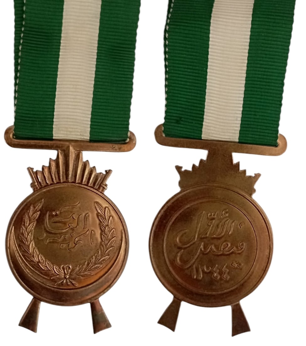 King Faisal’s War Medal (Nut al-Khidmat al-Amma), 1926, 1st Model: Breast Badge, 52x35 mm, Bronze, original suspension ring and ribbon. Mint stateI